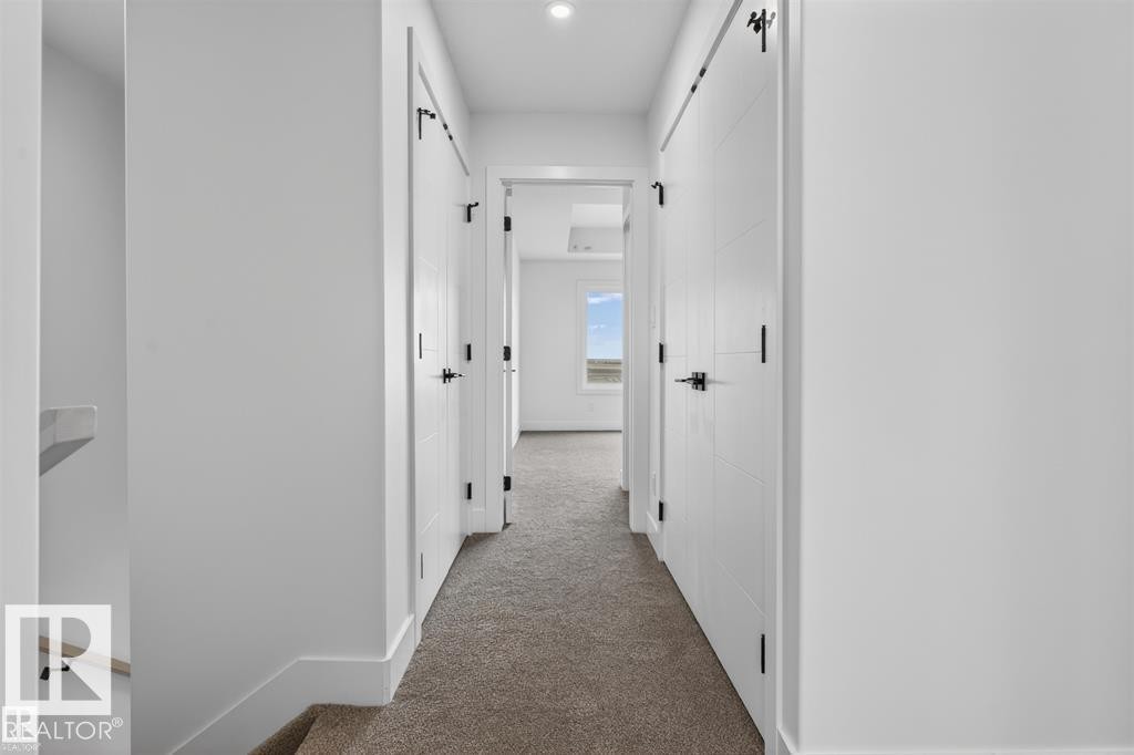 Carpeted hallway featuring multiple white paneled doors with matte black hardware - 43 River Birch Way, St. Albert, AB - Indoor Photo Showing Other Room
