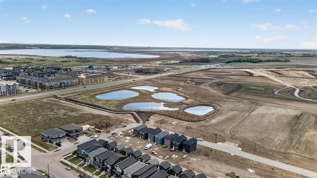 Aerial depiction of a developing neighborhood featuring multiple residential structures, bodies of water, and surrounding open land - 43 River Birch Way, St. Albert, AB - Outdoor With View