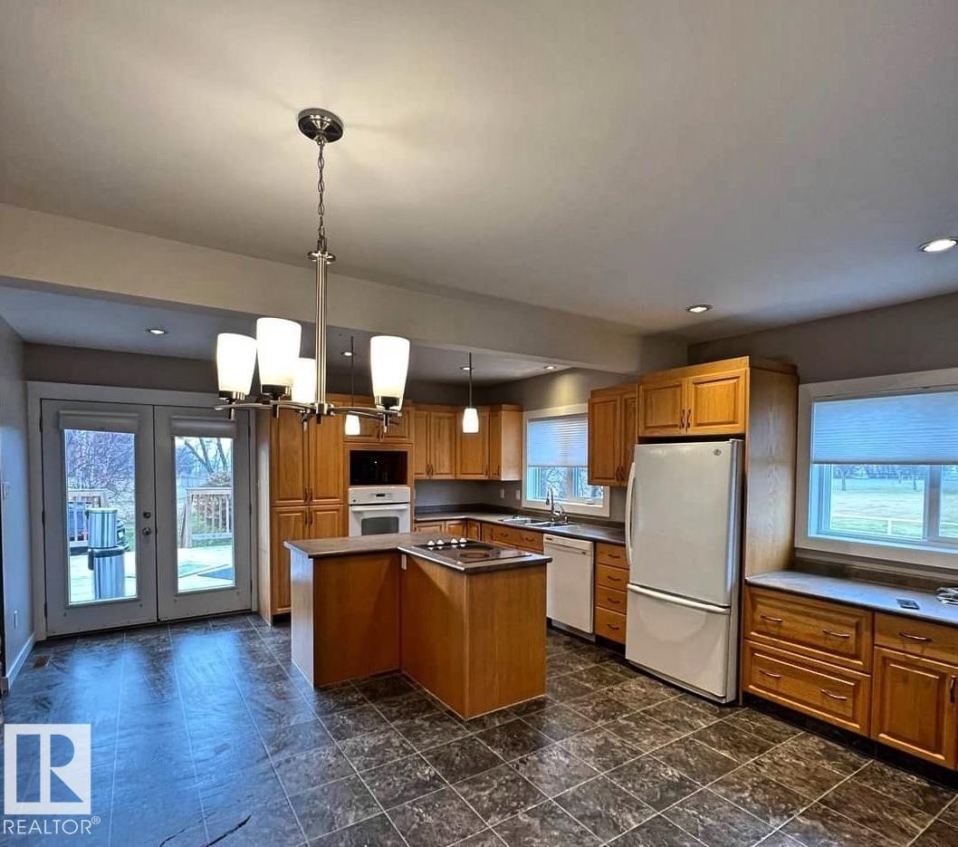 Kitchen featuring an L-shaped island with an integrated cooktop, wood-finish cabinetry, built-in oven, and recessed lighting - 3003 Park Avenue, Mallaig, AB - Indoor Photo Showing Kitchen