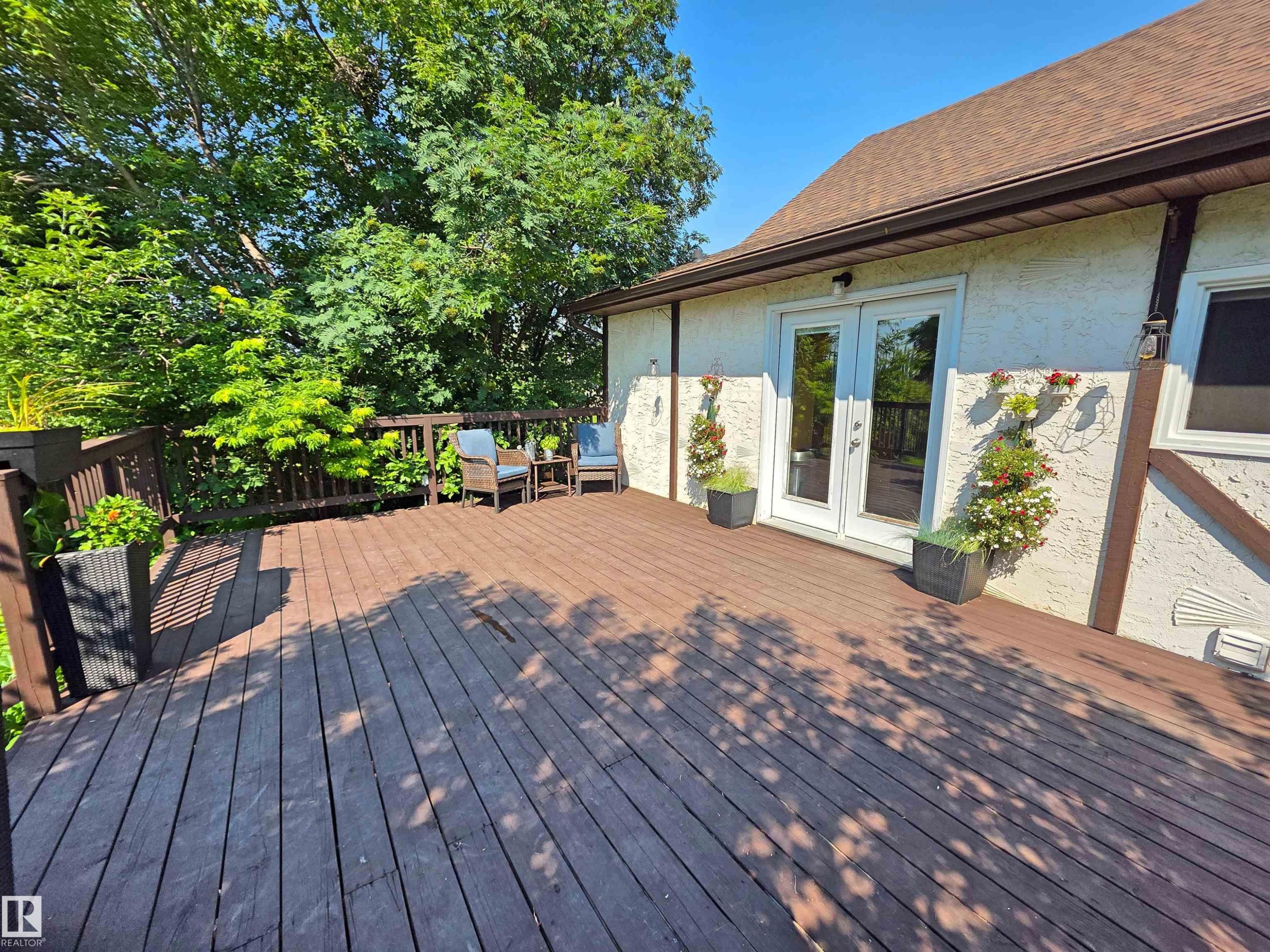 Expansive wood deck with a perimeter railing and mature tree canopy - 3003 Park Avenue, Mallaig, AB - Outdoor With Deck Patio Veranda With Exterior