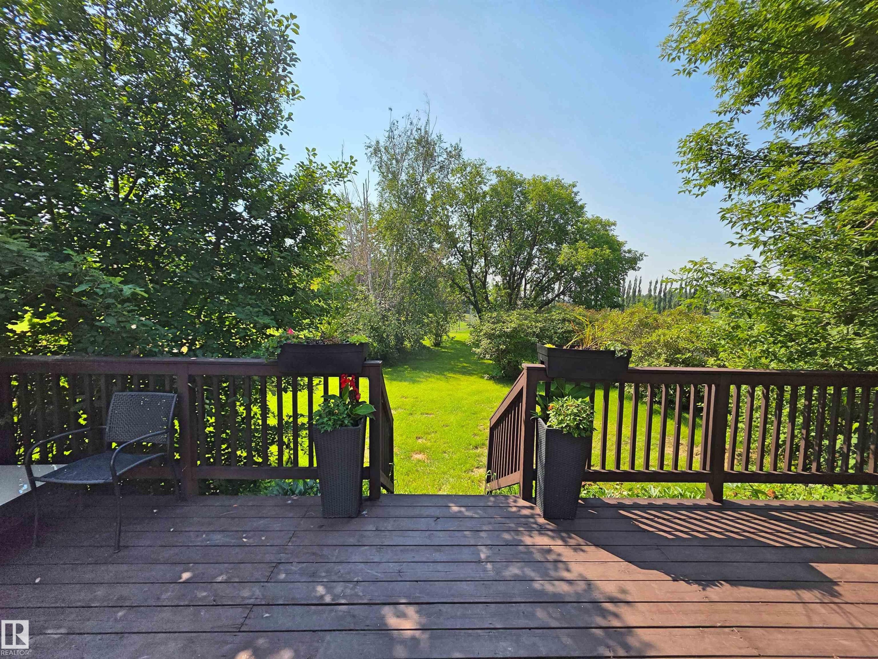Outdoor wood-finish deck featuring a slatted railing and steps descending to a grassy area - 3003 Park Avenue, Mallaig, AB - Outdoor With Deck Patio Veranda