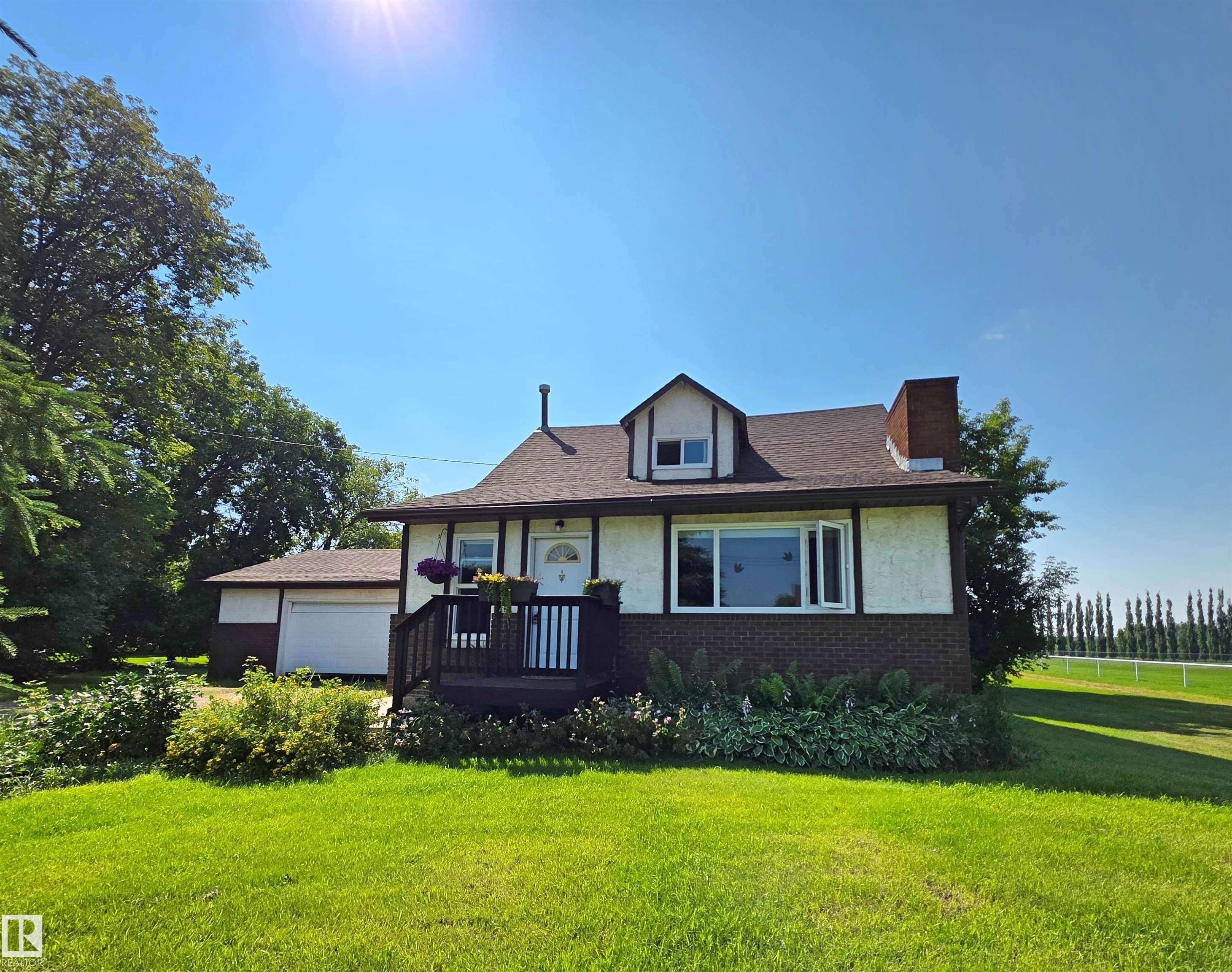 Front exterior featuring a brown shingle roof, white stucco siding with dark trim, and a brick base - 3003 Park Avenue, Mallaig, AB - Outdoor