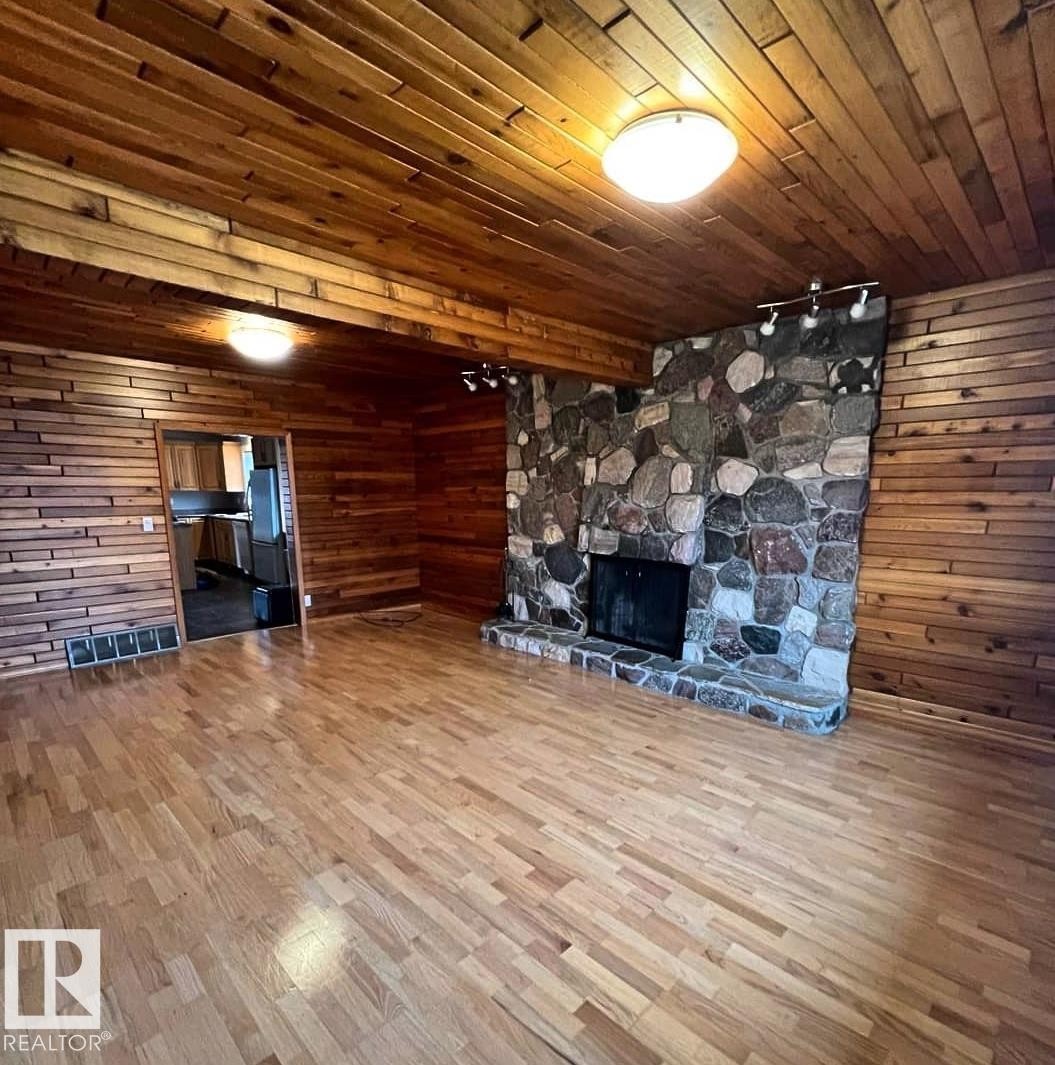 Spacious room featuring laminate flooring, a stone fireplace with hearth - 3003 Park Avenue, Mallaig, AB - Indoor With Fireplace