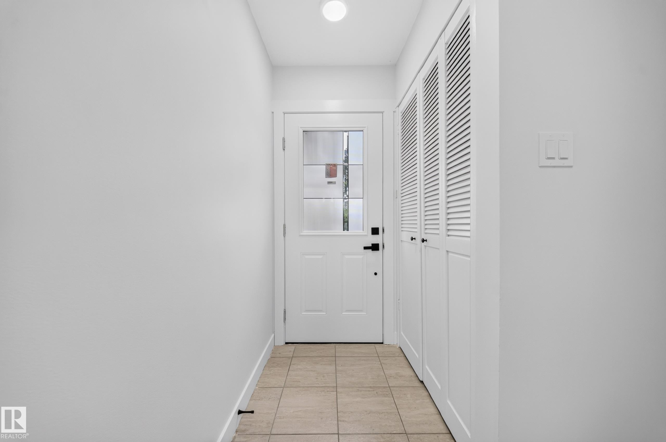 Entryway featuring a paneled door with glass inserts, matte black hardware, and an overhead flush-mount light - 5204 97A Avenue Nw, Edmonton, AB - Indoor Photo Showing Other Room