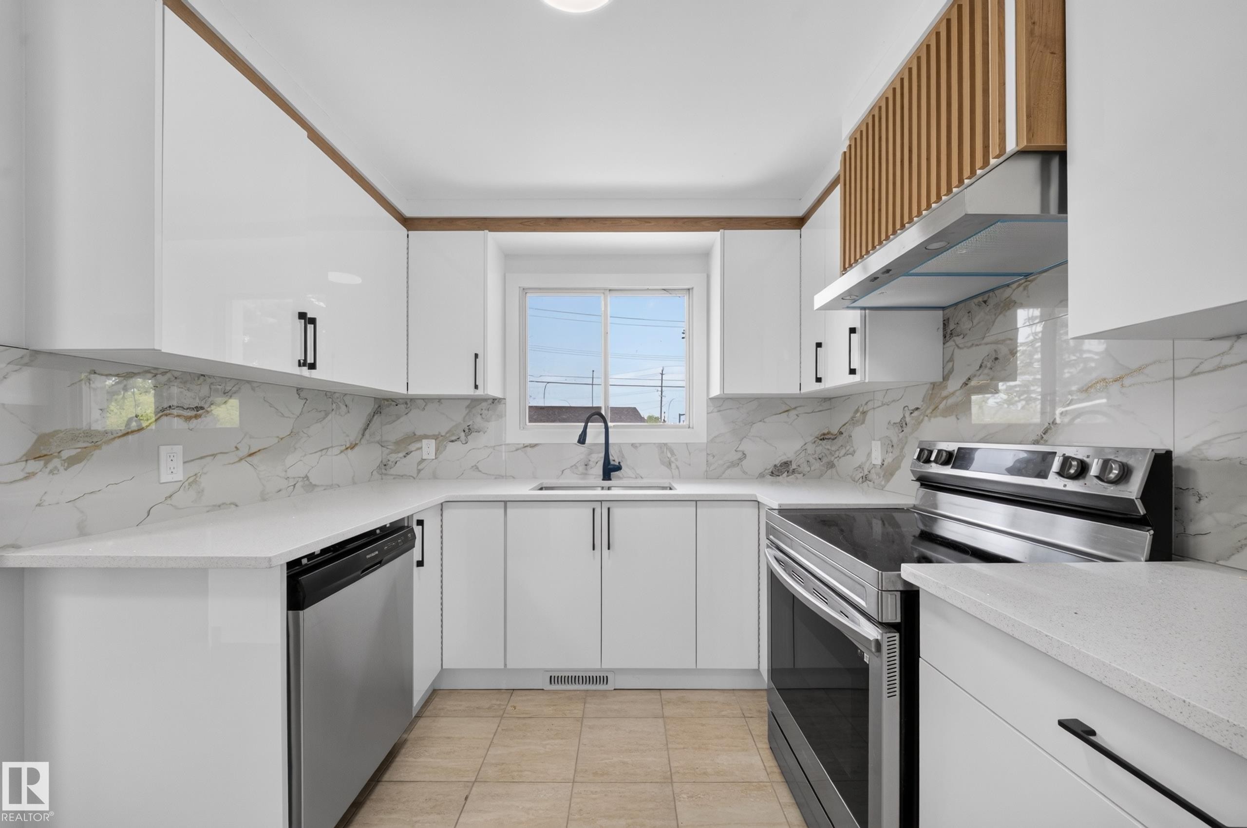 U-shaped kitchen featuring white high-gloss cabinetry with wood-finish accents, a black faucet, and stainless steel appliances - 5204 97A Avenue Nw, Edmonton, AB - Indoor Photo Showing Kitchen