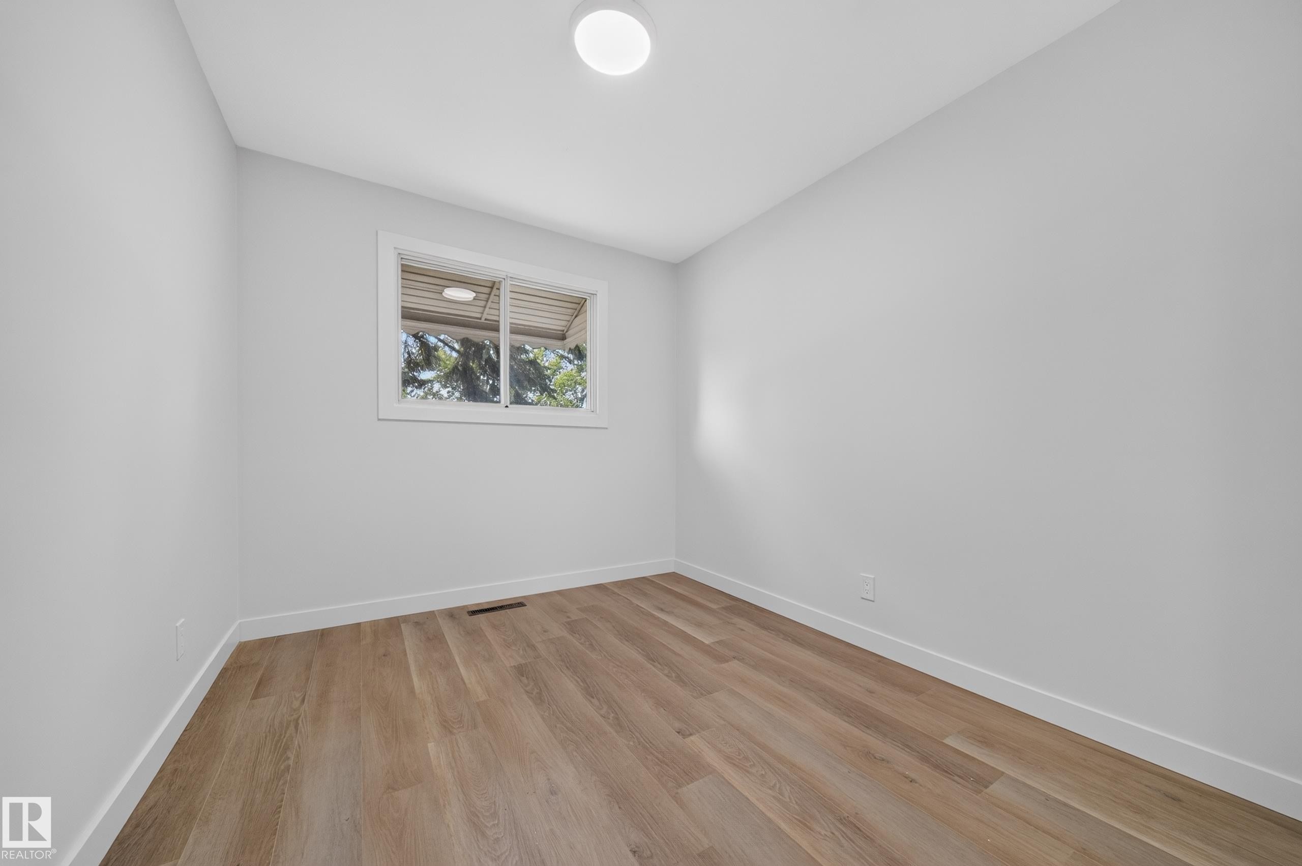 Room featuring light wood-finish flooring, white walls, and a single window with white trim - 5204 97A Avenue Nw, Edmonton, AB - Indoor Photo Showing Other Room