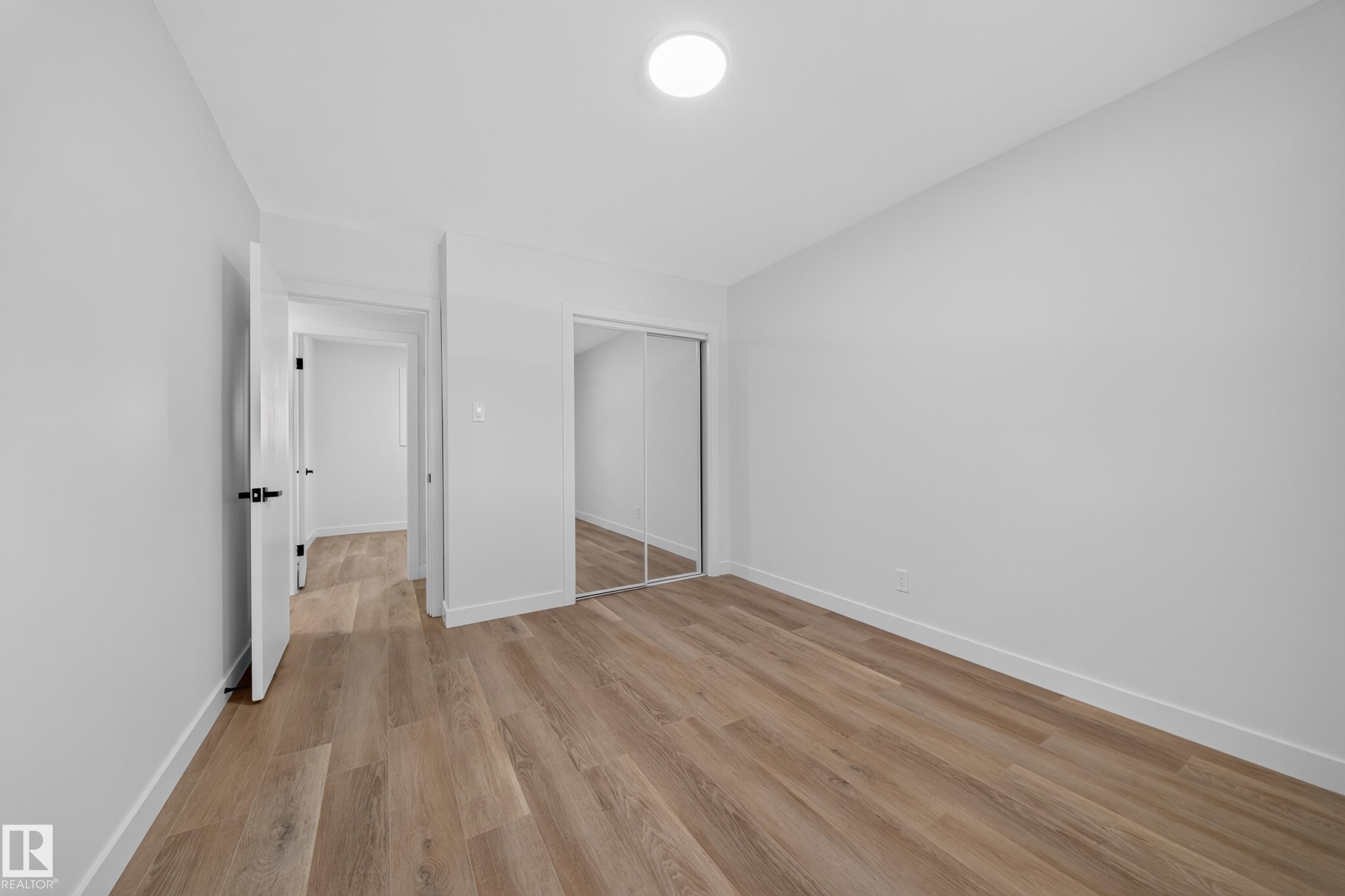 Light wood-finish flooring with white baseboards throughout - 5204 97A Avenue Nw, Edmonton, AB - Indoor Photo Showing Other Room