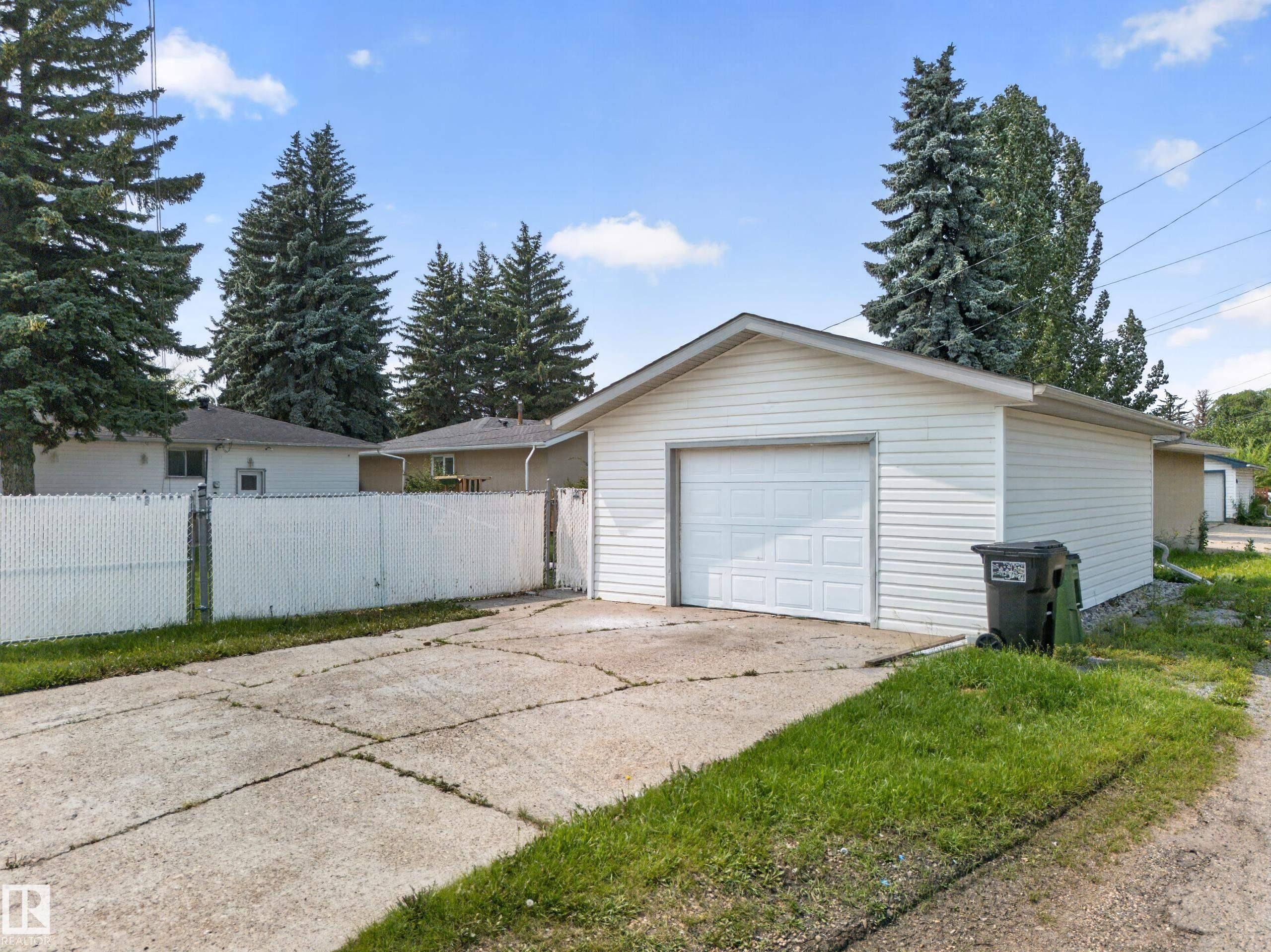 Detached garage with white vinyl siding, a white overhead door, and a concrete driveway - 5204 97A Avenue Nw, Edmonton, AB - Outdoor With Exterior