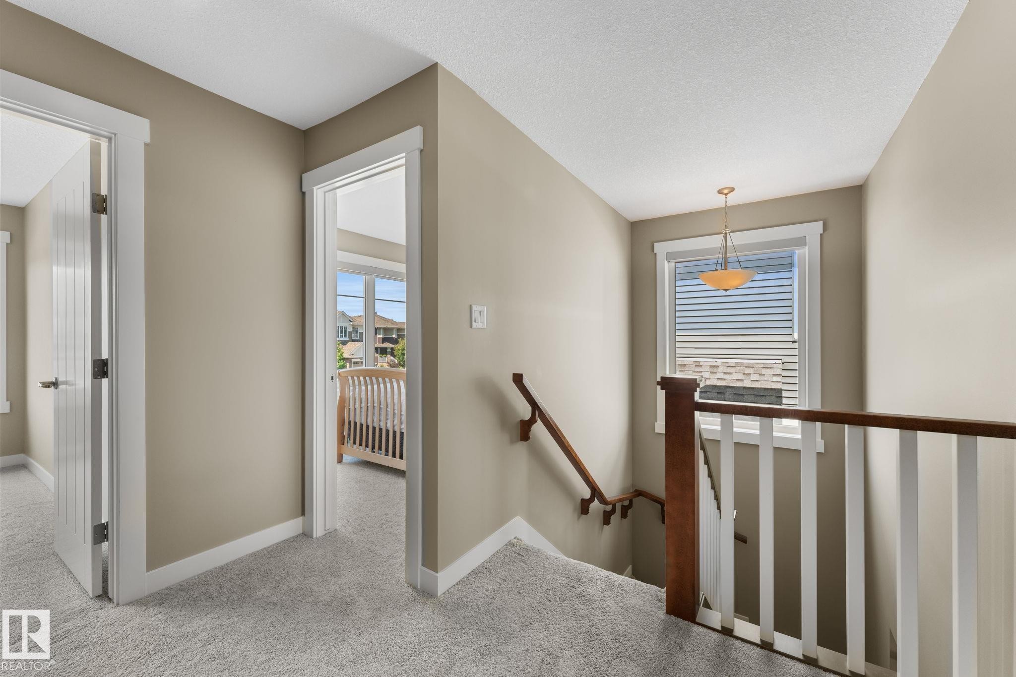 Upper landing with light gray carpeting, white trim, and a warm neutral wall color - 3413 Cameron Heights Cove Nw, Edmonton, AB - Indoor Photo Showing Other Room