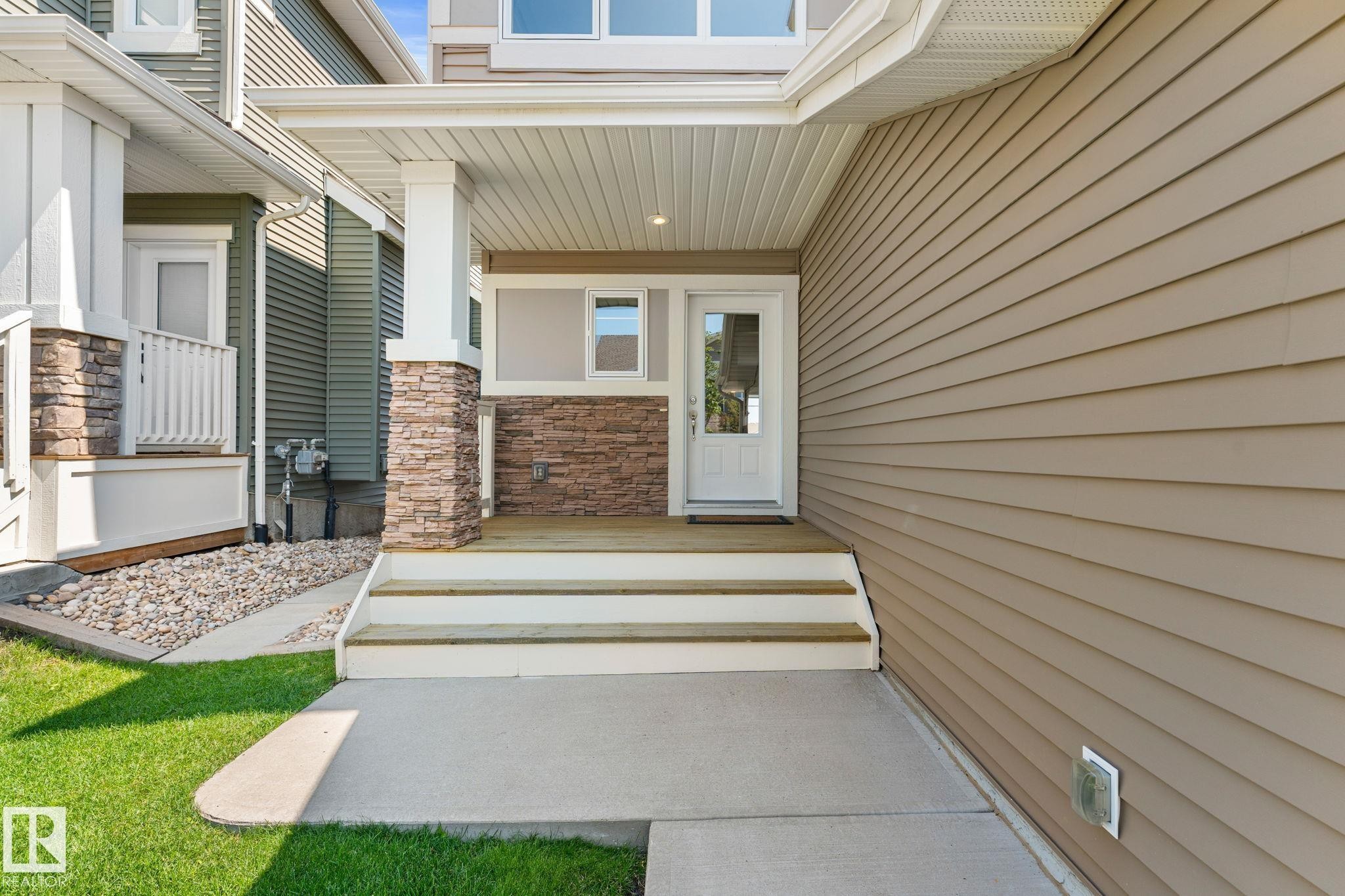 Covered entry with stone veneer accents and a paneled white door featuring a top-half window - 3413 Cameron Heights Cove Nw, Edmonton, AB - Outdoor With Exterior