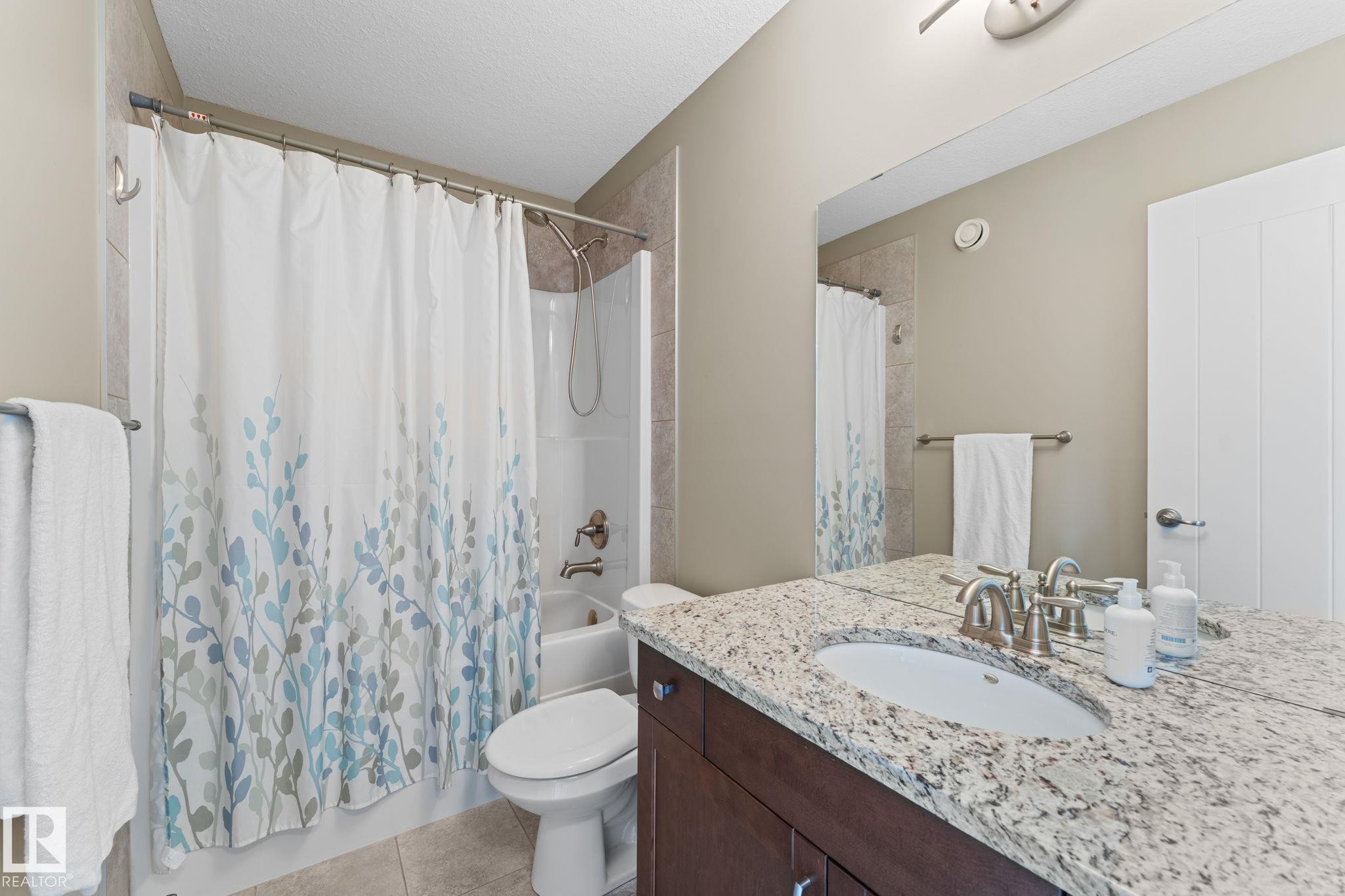 Bathroom featuring a built-in vanity with a speckled countertop, an undermount sink with a brushed nickel faucet, and a large mirror - 3413 Cameron Heights Cove Nw, Edmonton, AB - Indoor Photo Showing Bathroom