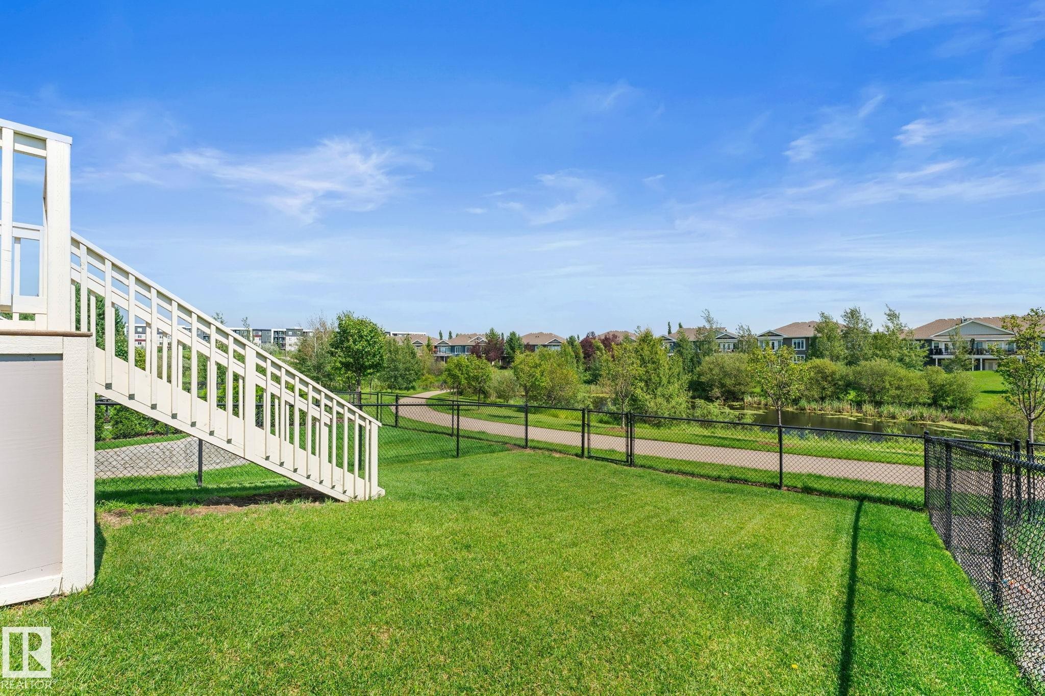 Expansive green lawn with a white exterior staircase providing access to an upper level - 3413 Cameron Heights Cove Nw, Edmonton, AB - Outdoor
