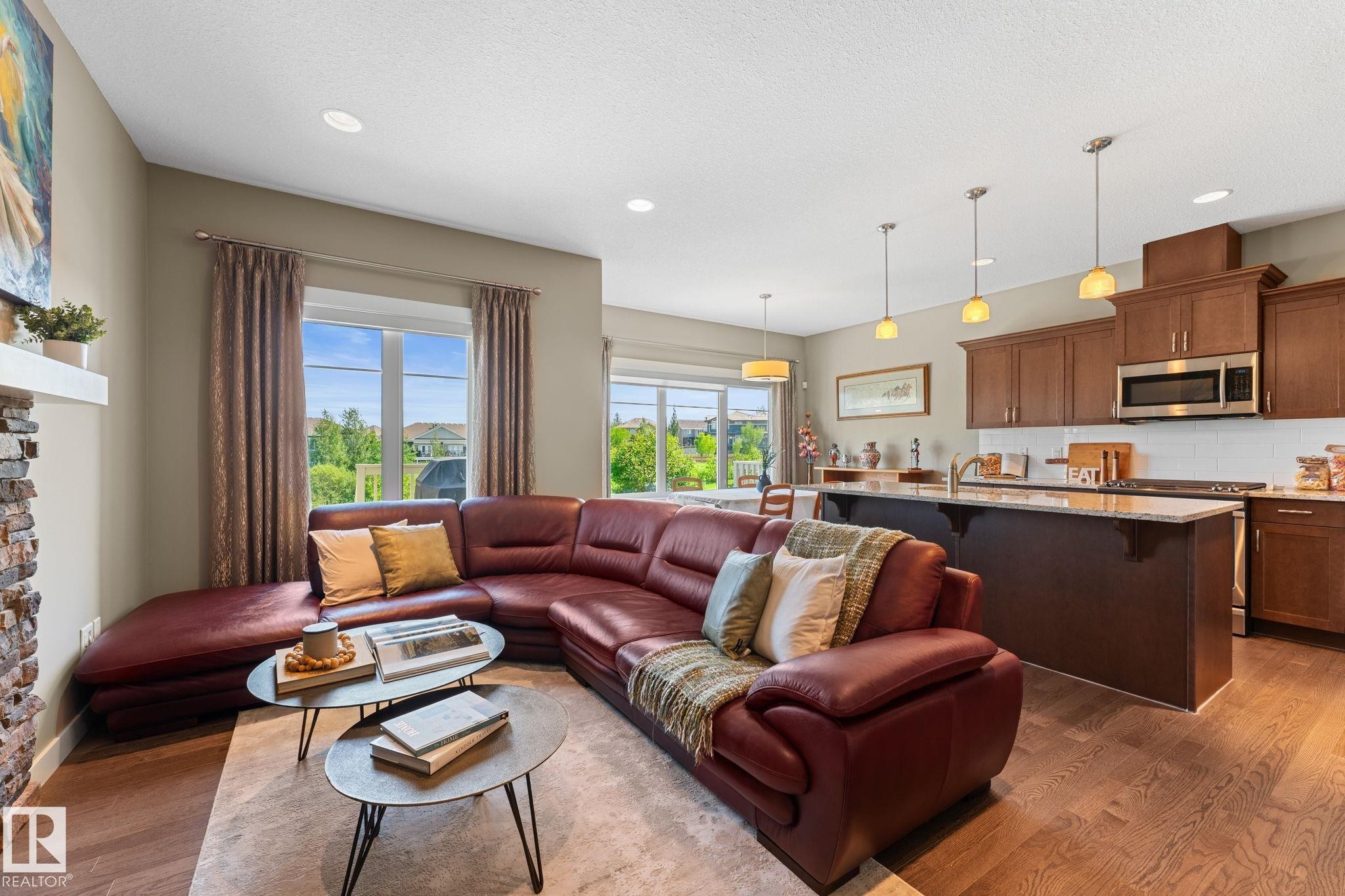 Open-concept living space with wood-finish flooring, recessed lighting, and large windows - 3413 Cameron Heights Cove Nw, Edmonton, AB - Indoor