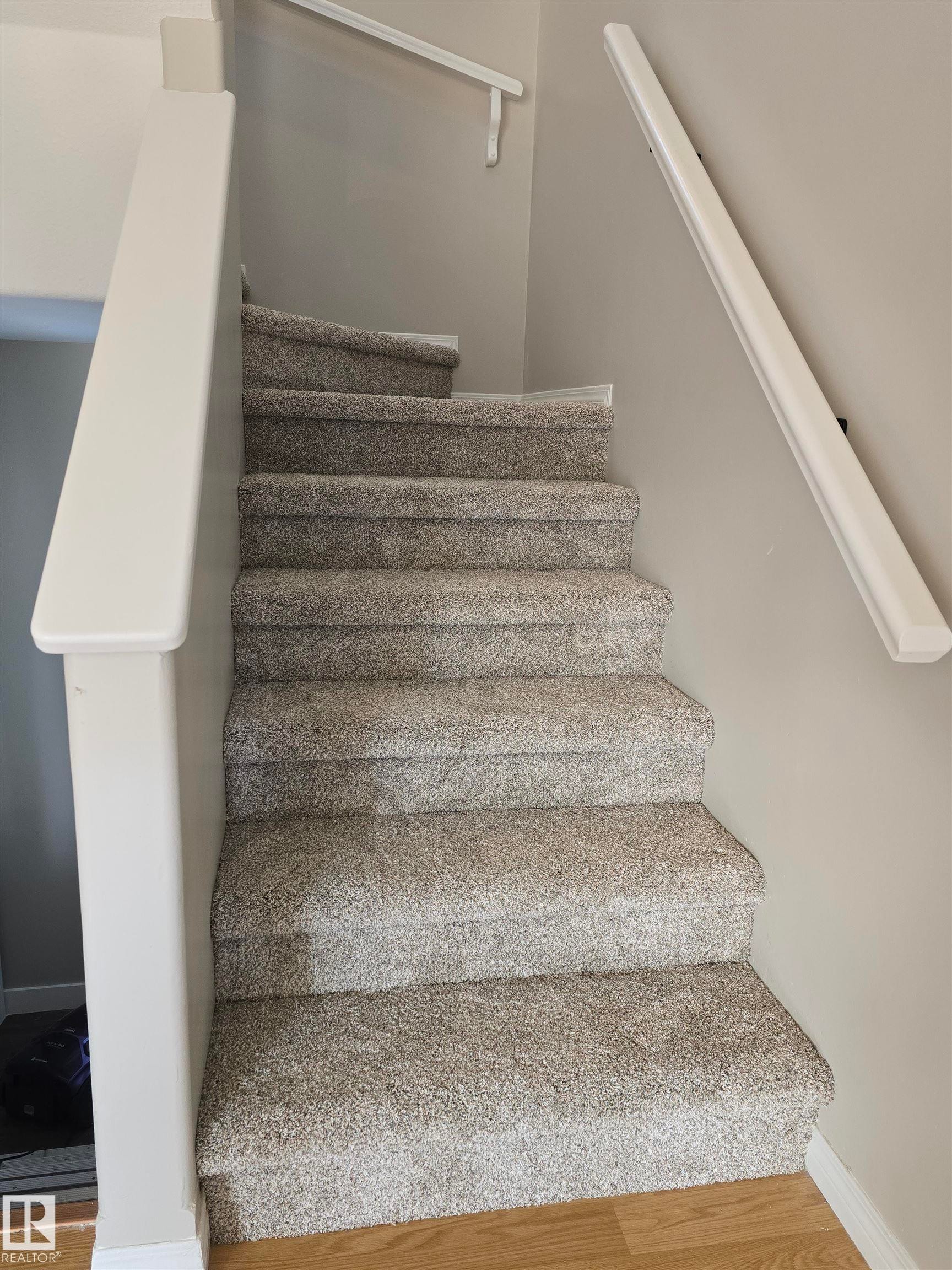 Carpeted staircase with light gray walls, white balustrade, and white handrails - 4120 47 Street, Drayton Valley, AB - Indoor Photo Showing Other Room