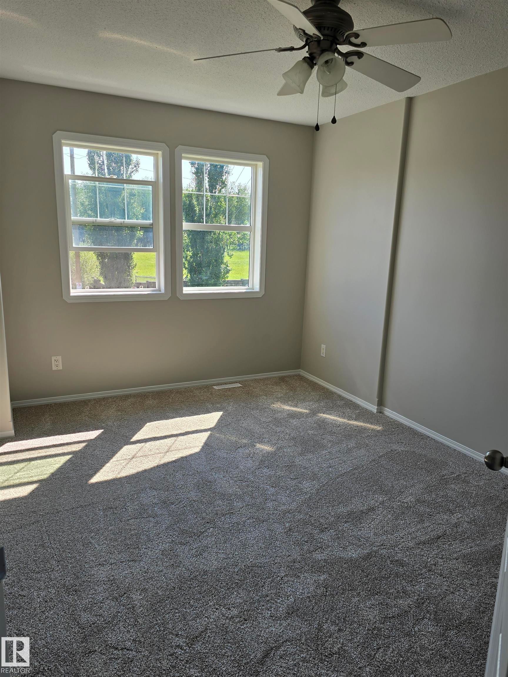 Room featuring two windows, neutral-toned walls, and a ceiling fan with integrated lighting - 4120 47 Street, Drayton Valley, AB - Indoor Photo Showing Other Room