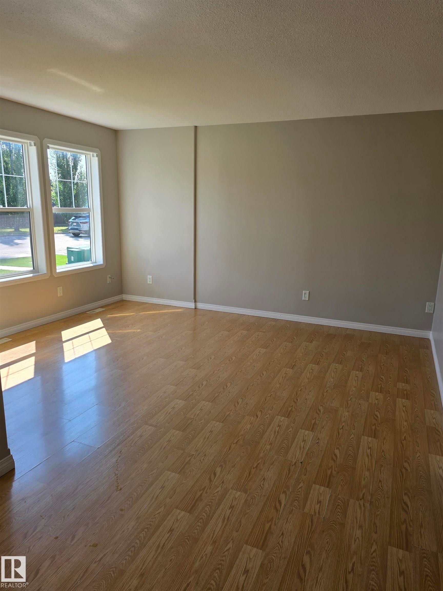 Expansive room featuring wood-finish flooring, light neutral wall tones, and white baseboards - 4120 47 Street, Drayton Valley, AB - Indoor Photo Showing Other Room