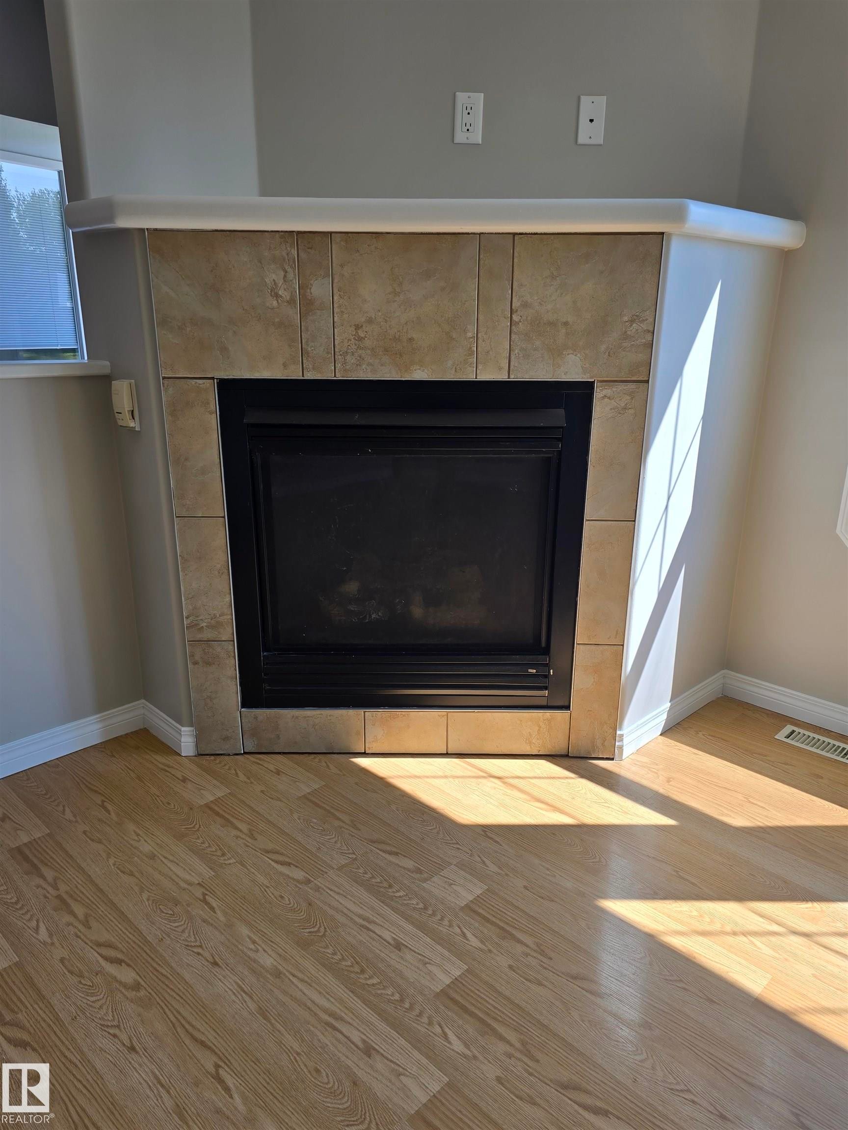 Corner fireplace with a tile surround and a light-colored mantel - 4120 47 Street, Drayton Valley, AB - Indoor Photo Showing Living Room With Fireplace