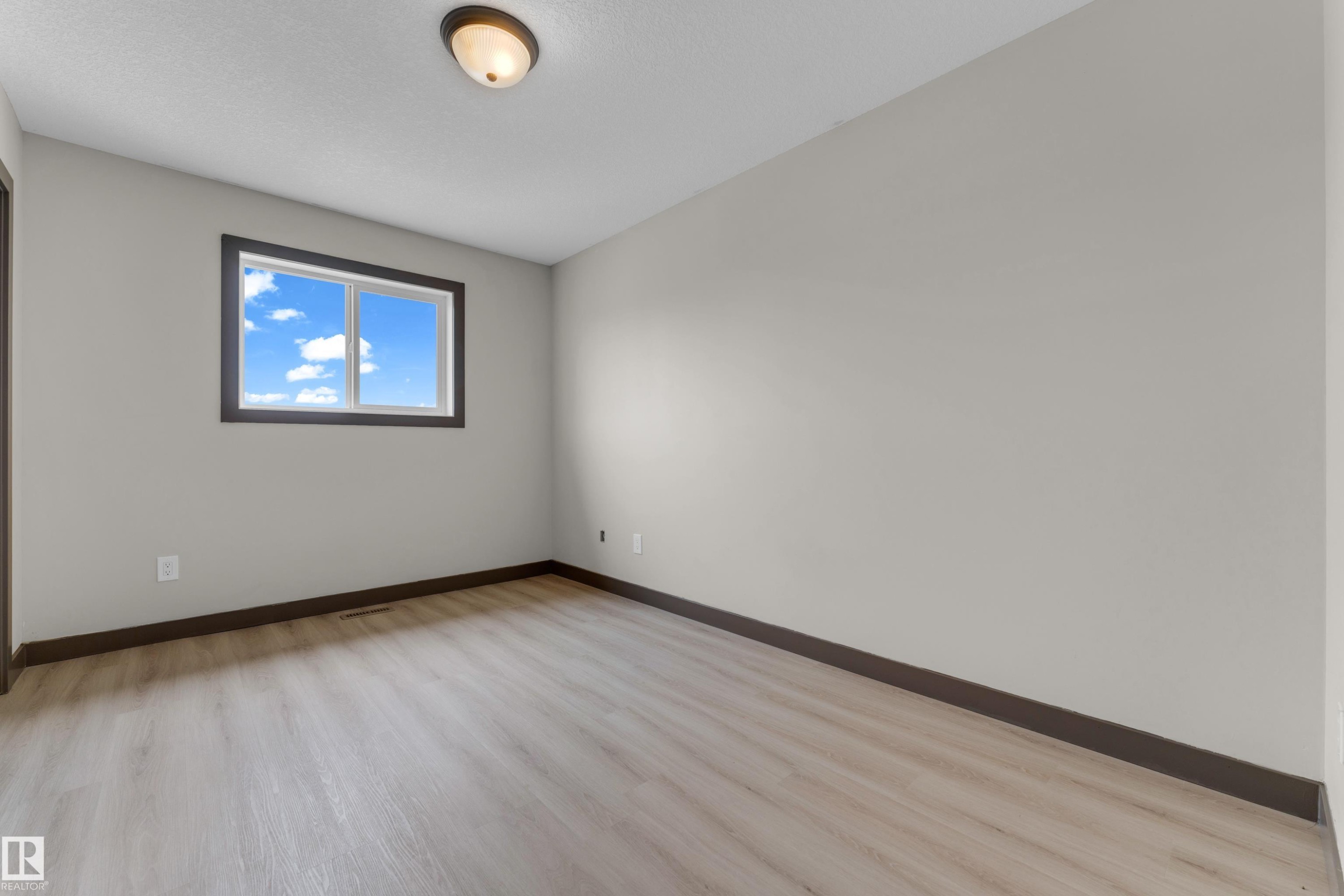 Room featuring light wood-finish flooring, a neutral wall color, and dark trim - 11817 37 Street Nw, Edmonton, AB - Indoor Photo Showing Other Room