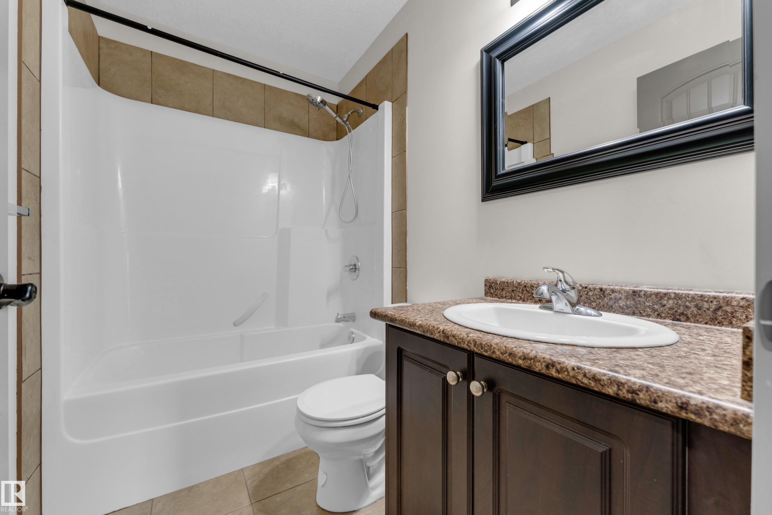 Bathroom vanity featuring a dark wood-finish cabinet with double doors and knob hardware, paired with a speckled countertop and an oval undermount sink - 11817 37 Street Nw, Edmonton, AB - Indoor Photo Showing Bathroom