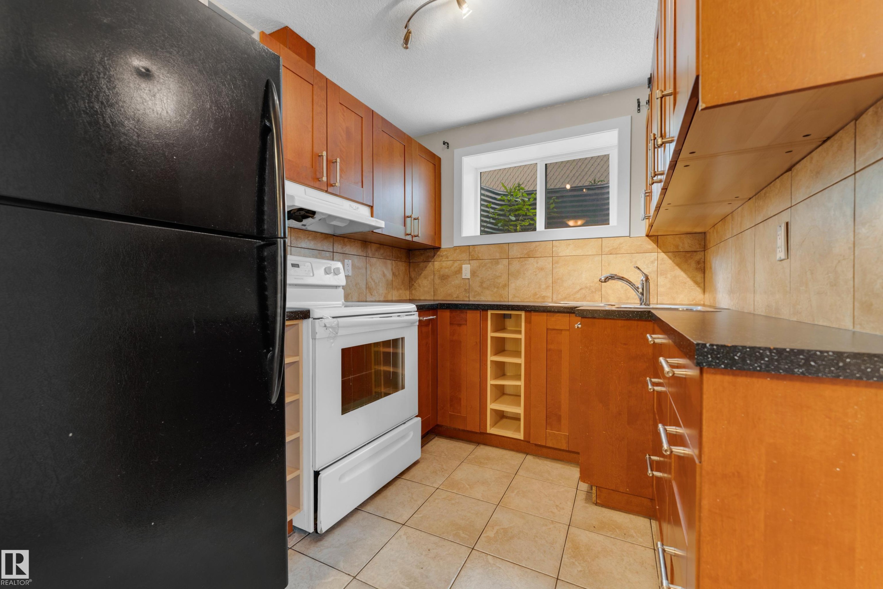 Compact kitchen featuring wood cabinetry, a tiled backsplash, and dark speckled countertops - 11817 37 Street Nw, Edmonton, AB - Indoor Photo Showing Kitchen
