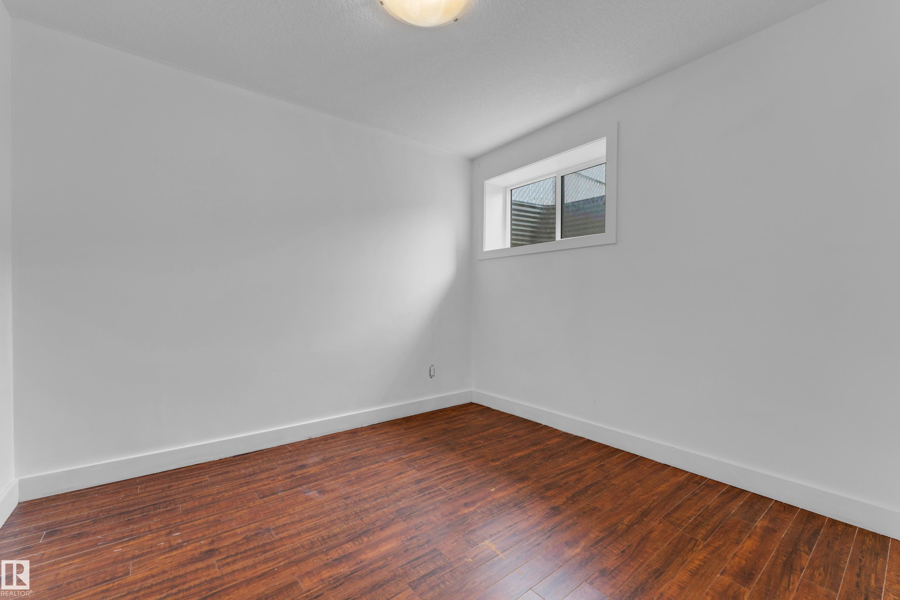 Room featuring wood-finish flooring, white painted walls, a flush-mount ceiling light fixture, and a window with white trim - 11817 37 Street Nw, Edmonton, AB - Indoor Photo Showing Other Room