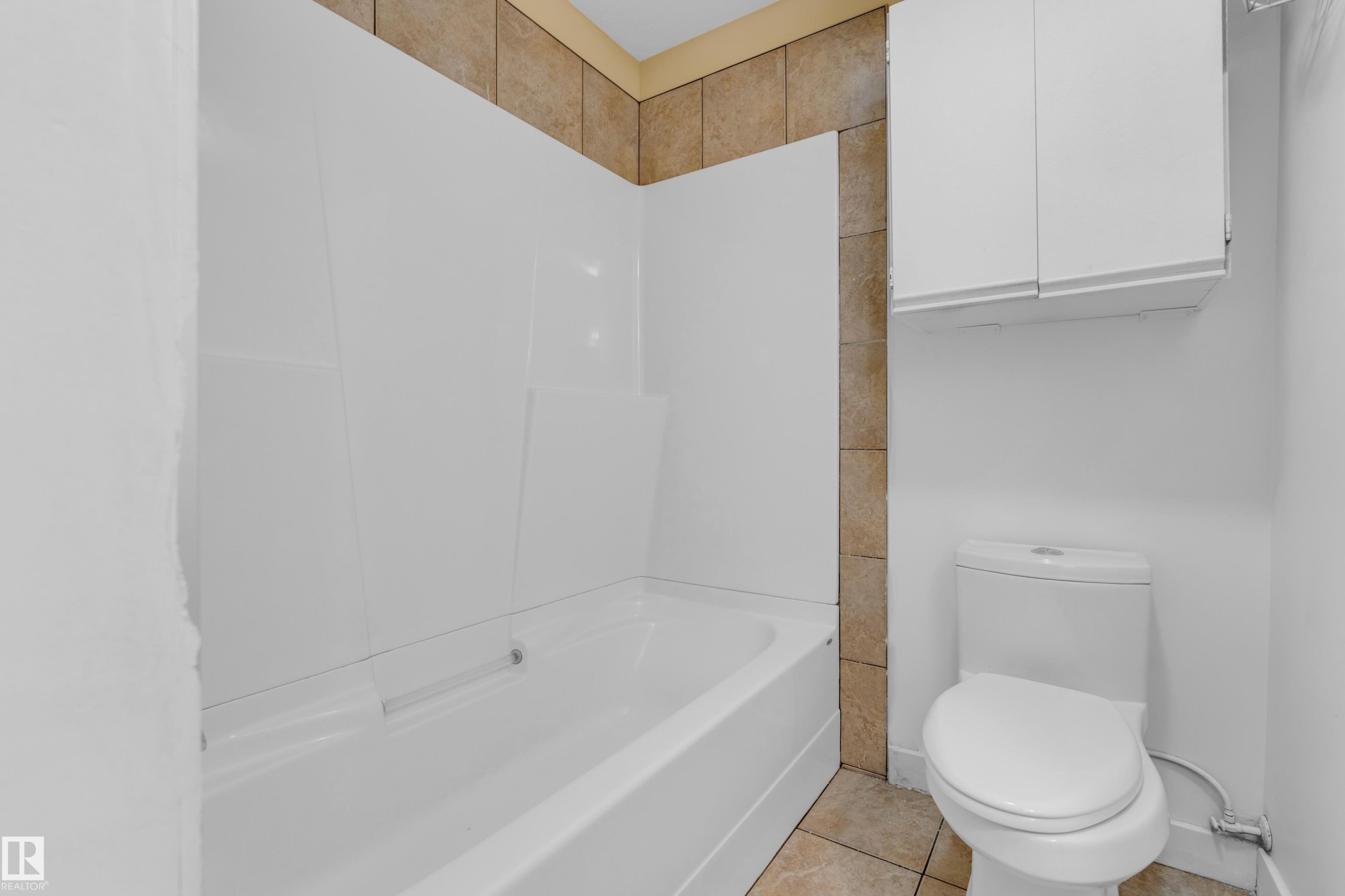 White bathtub and shower surround with neutral-toned wall tiling - 11817 37 Street Nw, Edmonton, AB - Indoor Photo Showing Bathroom