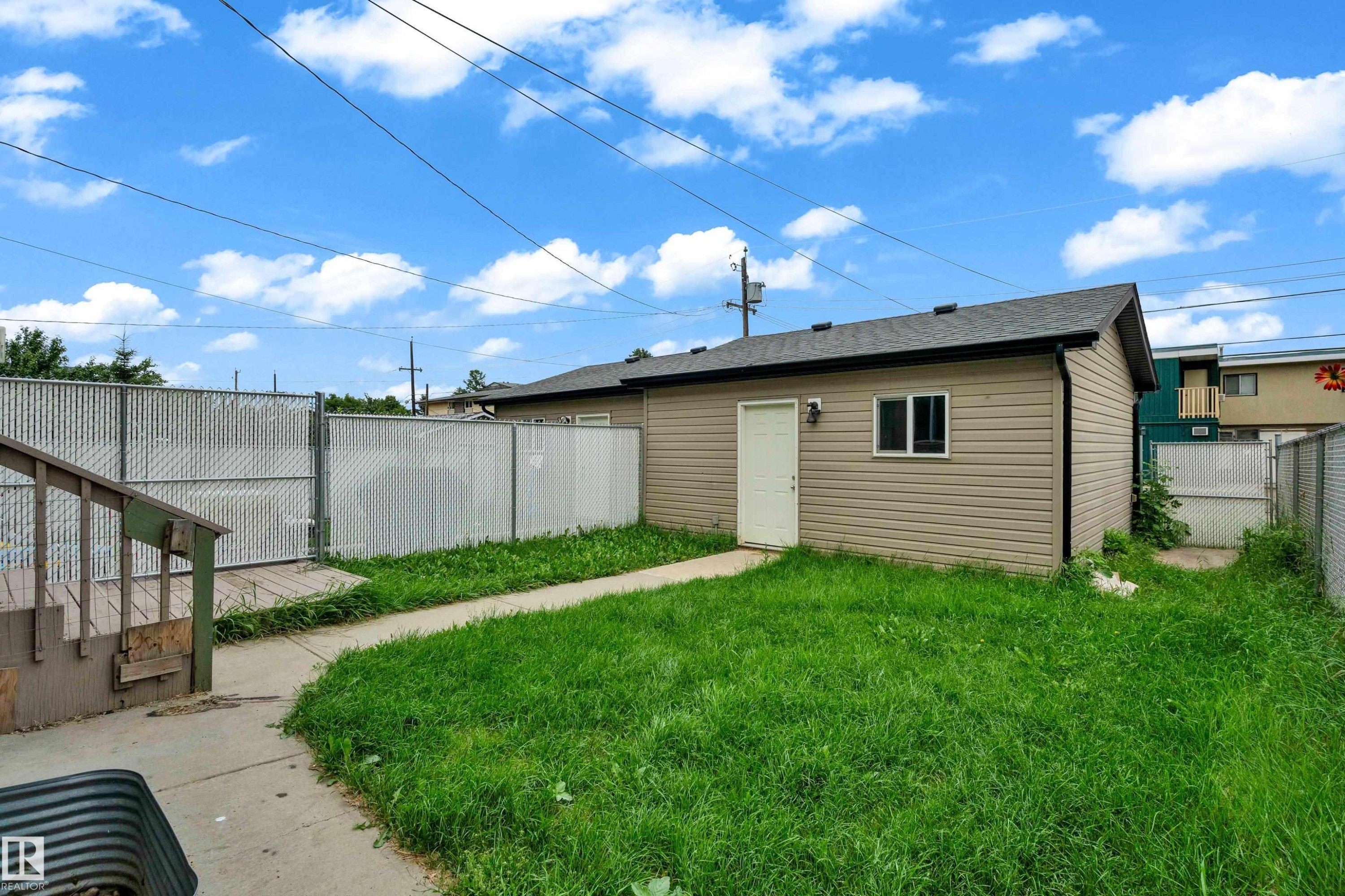 Detached structure featuring light beige siding, an asphalt shingle roof, and a white entry door - 11817 37 Street Nw, Edmonton, AB - Outdoor