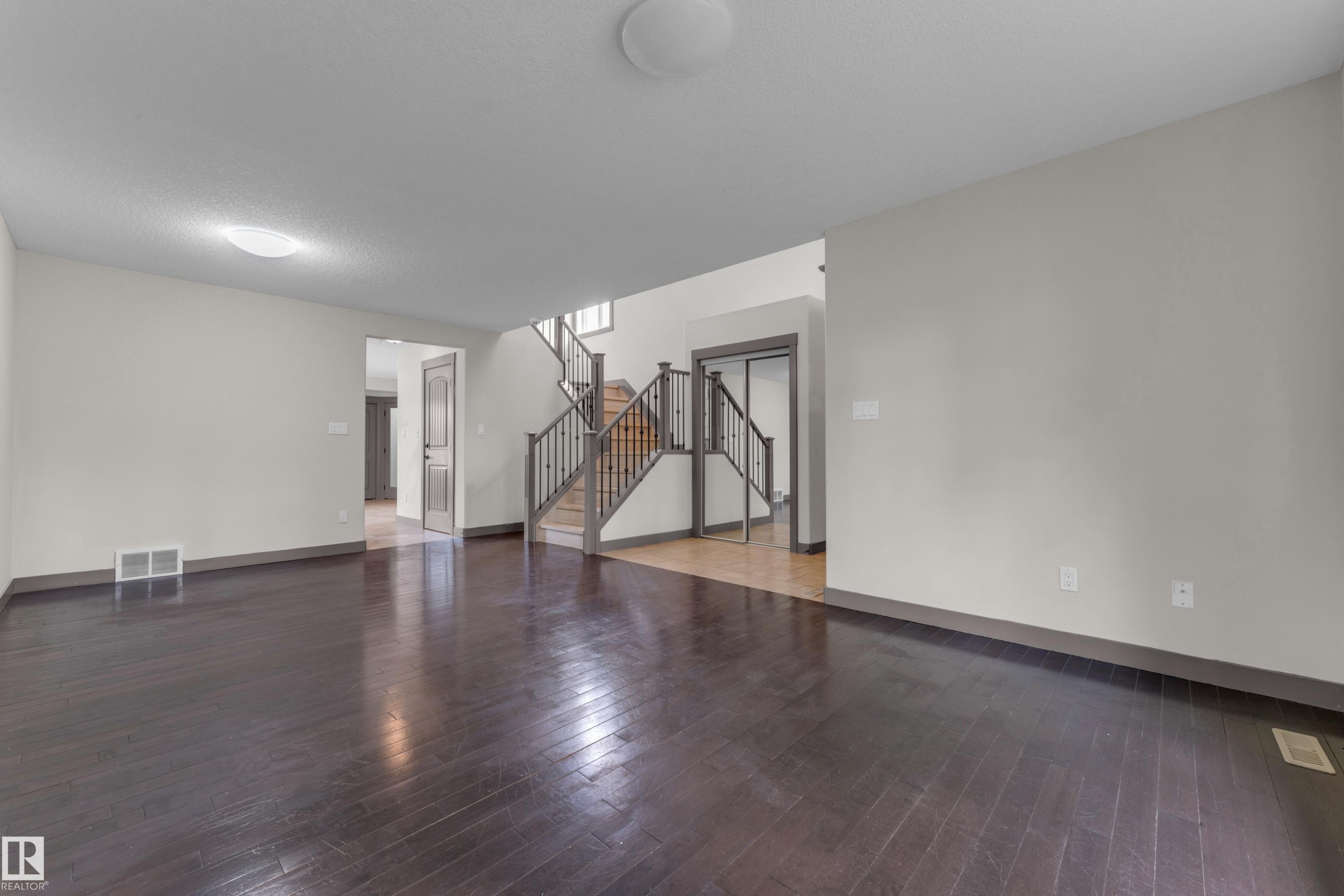 Expansive room featuring dark wood-finish flooring, light-toned walls, and a visible air vent - 11817 37 Street Nw, Edmonton, AB - Indoor Photo Showing Other Room