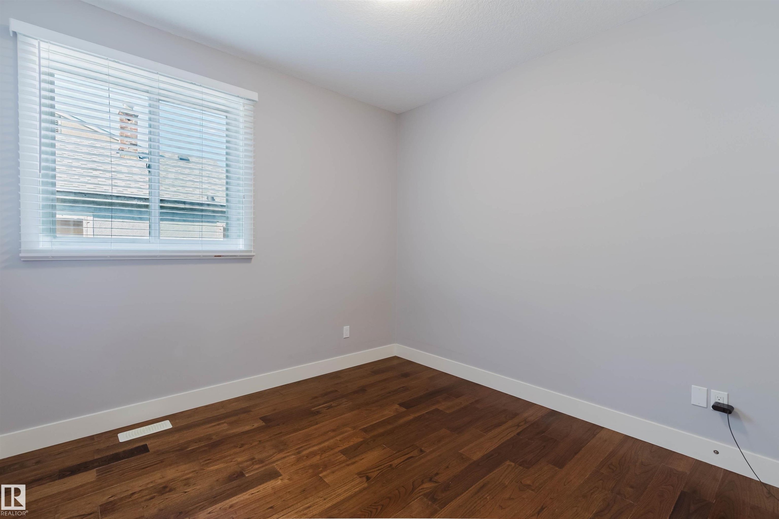 Room featuring wood-finish flooring, light grey painted walls, and white baseboards - 10626 81 Avenue Nw, Edmonton, AB - Indoor Photo Showing Other Room