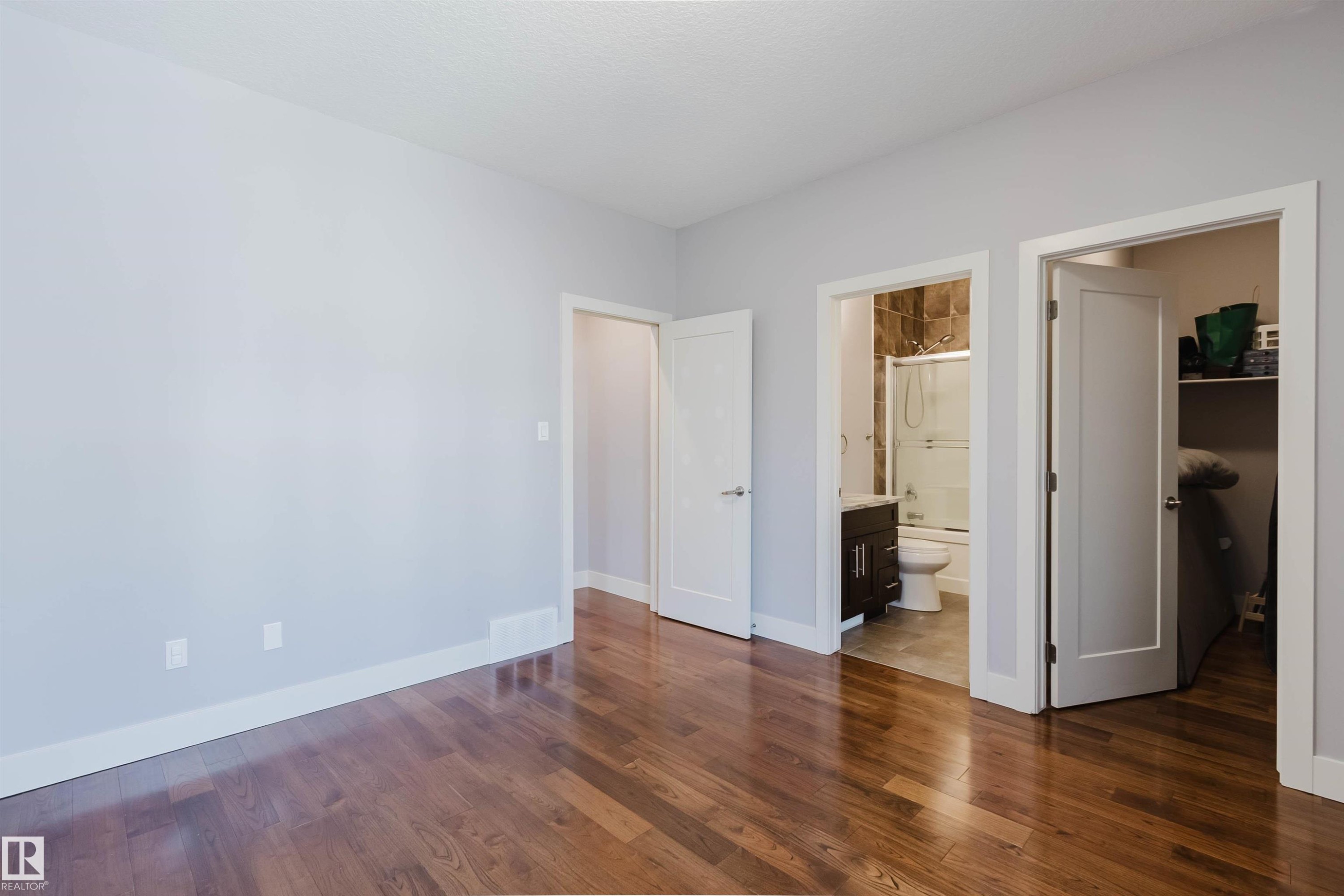 Spacious room featuring wood-finish flooring, light grey walls, white trim, and white interior doors - 10626 81 Avenue Nw, Edmonton, AB - Indoor Photo Showing Other Room