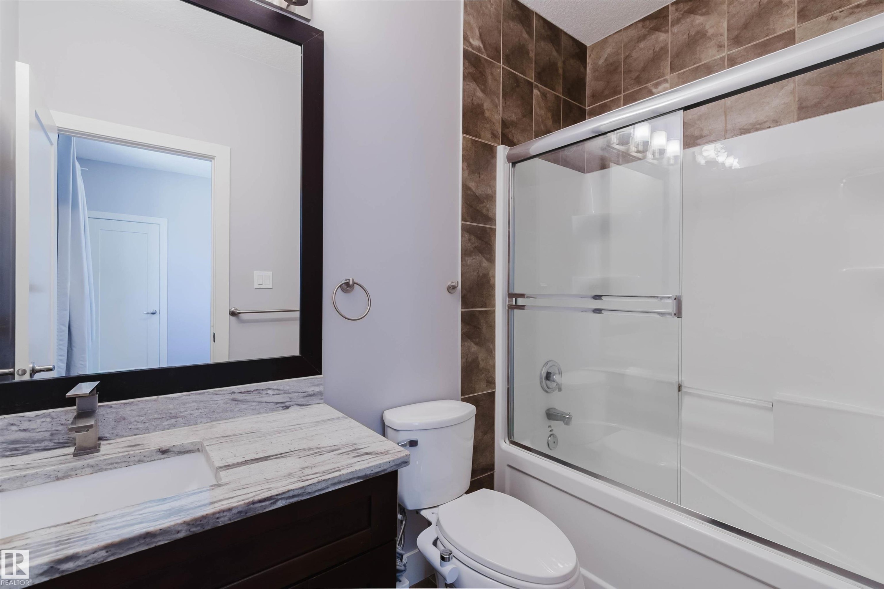 Bathroom featuring a dark wood-finish vanity with a light-toned patterned countertop, an undermount rectangular sink, and a brushed nickel faucet - 10626 81 Avenue Nw, Edmonton, AB - Indoor Photo Showing Bathroom