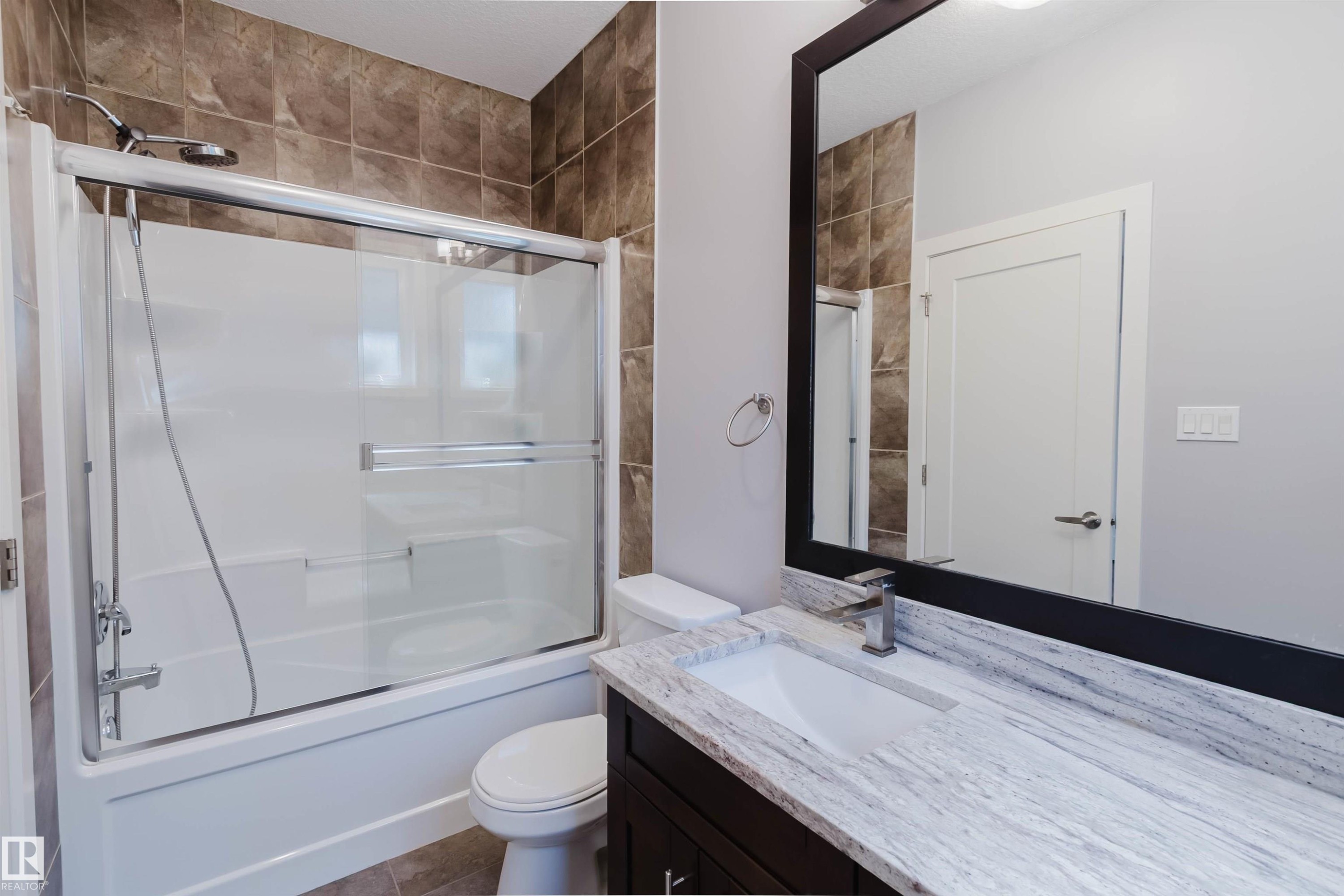 Bathroom featuring a tub/shower combination with sliding glass doors, brown tile surround, and chrome fixtures - 10626 81 Avenue Nw, Edmonton, AB - Indoor Photo Showing Bathroom