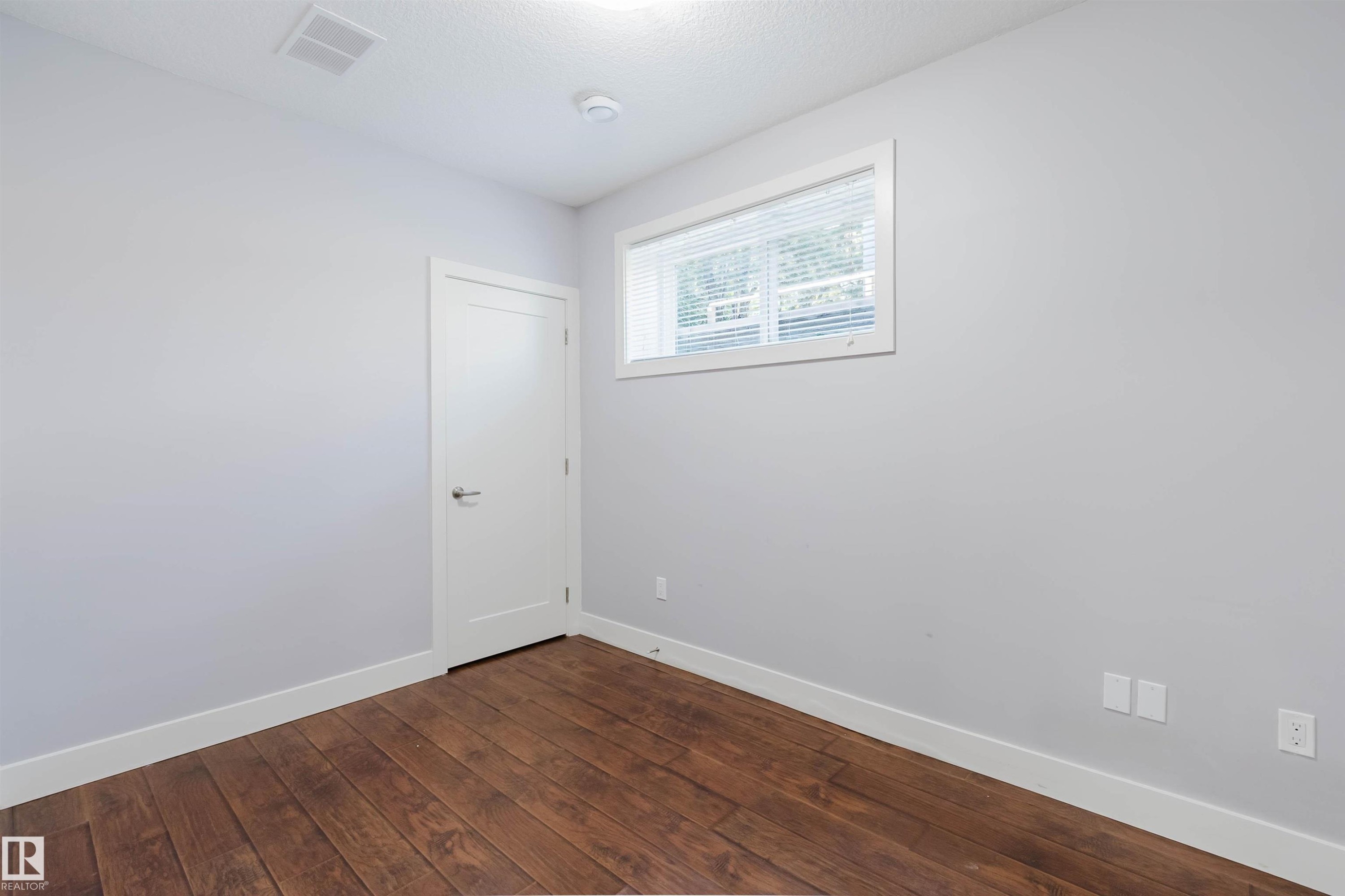 Room featuring wood-finish flooring, white baseboards, and light gray walls - 10626 81 Avenue Nw, Edmonton, AB - Indoor Photo Showing Other Room