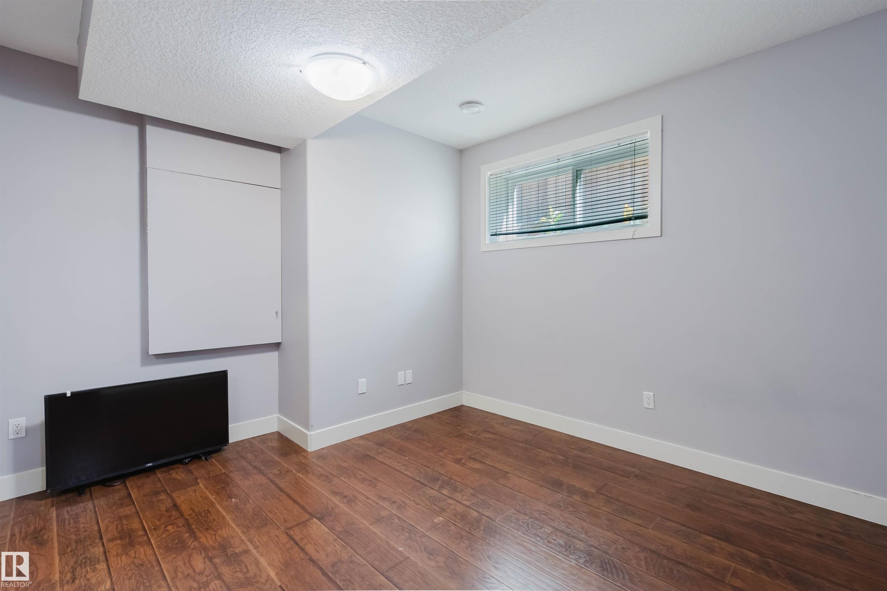 Room featuring wood-finish flooring, light grey walls, and white baseboards - 10626 81 Avenue Nw, Edmonton, AB - Indoor Photo Showing Other Room