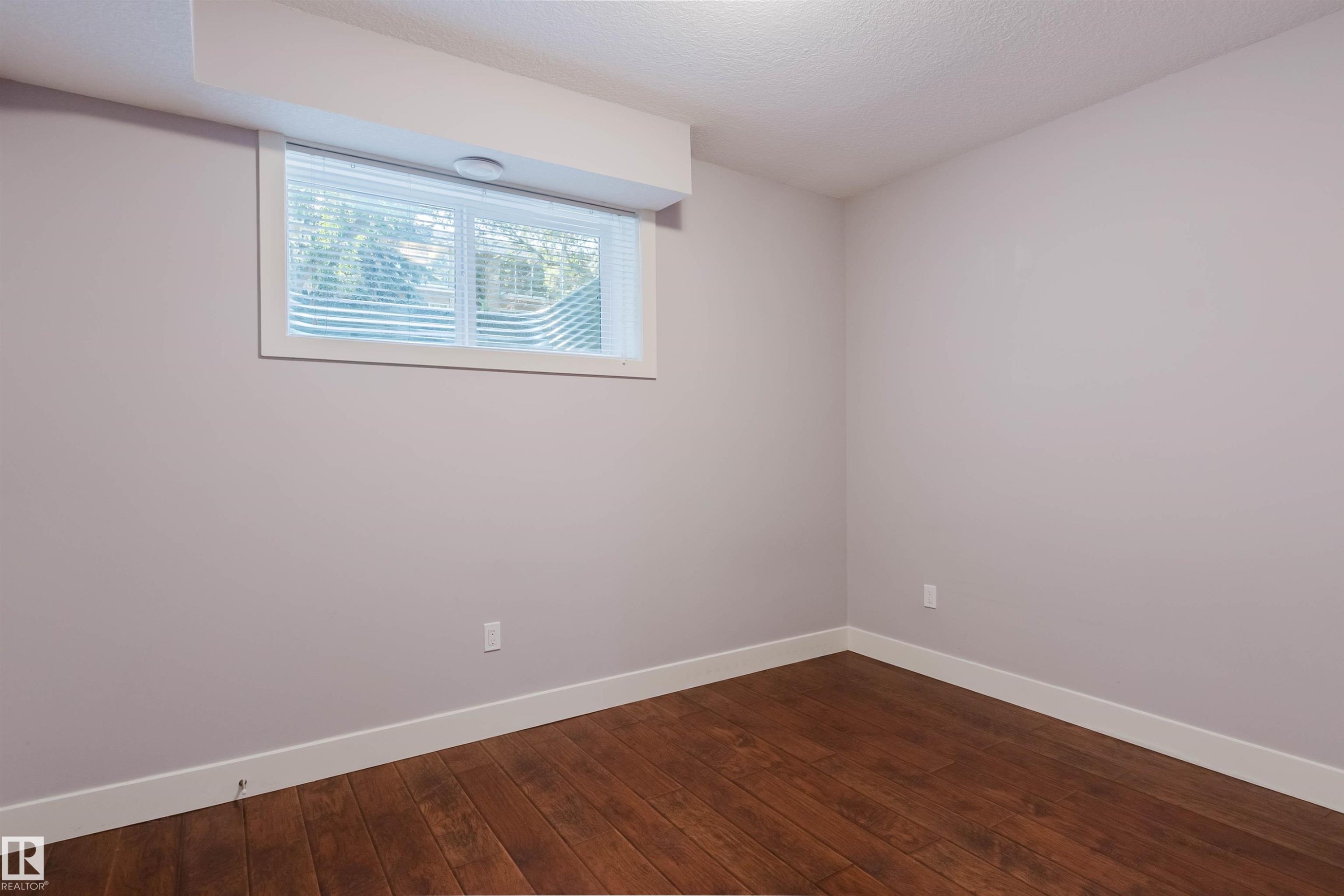 Spacious room featuring wood-finish flooring, light gray walls, and white trim - 10626 81 Avenue Nw, Edmonton, AB - Indoor Photo Showing Other Room
