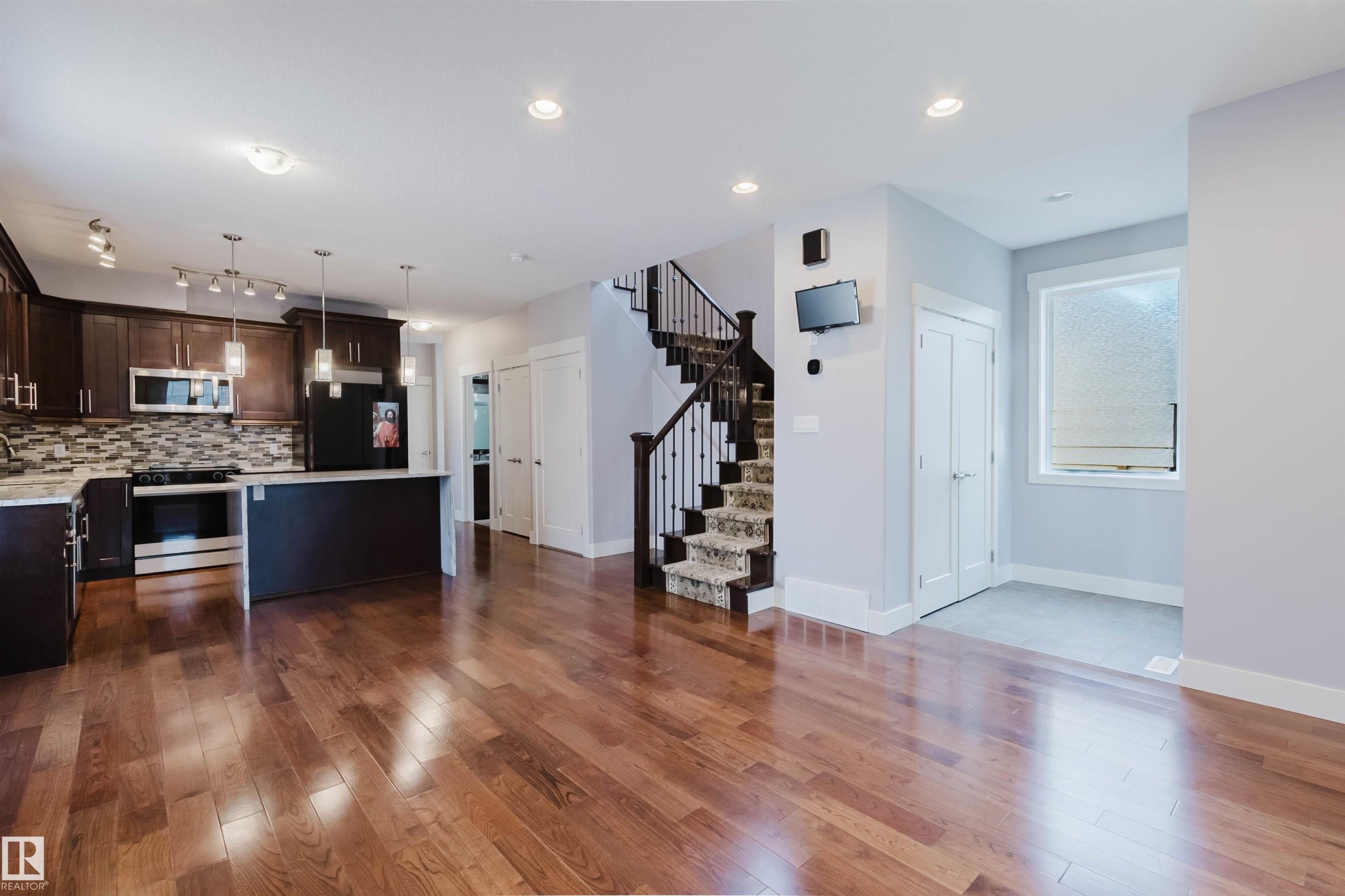Spacious open-concept living area featuring wood-finish flooring - 10626 81 Avenue Nw, Edmonton, AB - Indoor Photo Showing Kitchen With Upgraded Kitchen