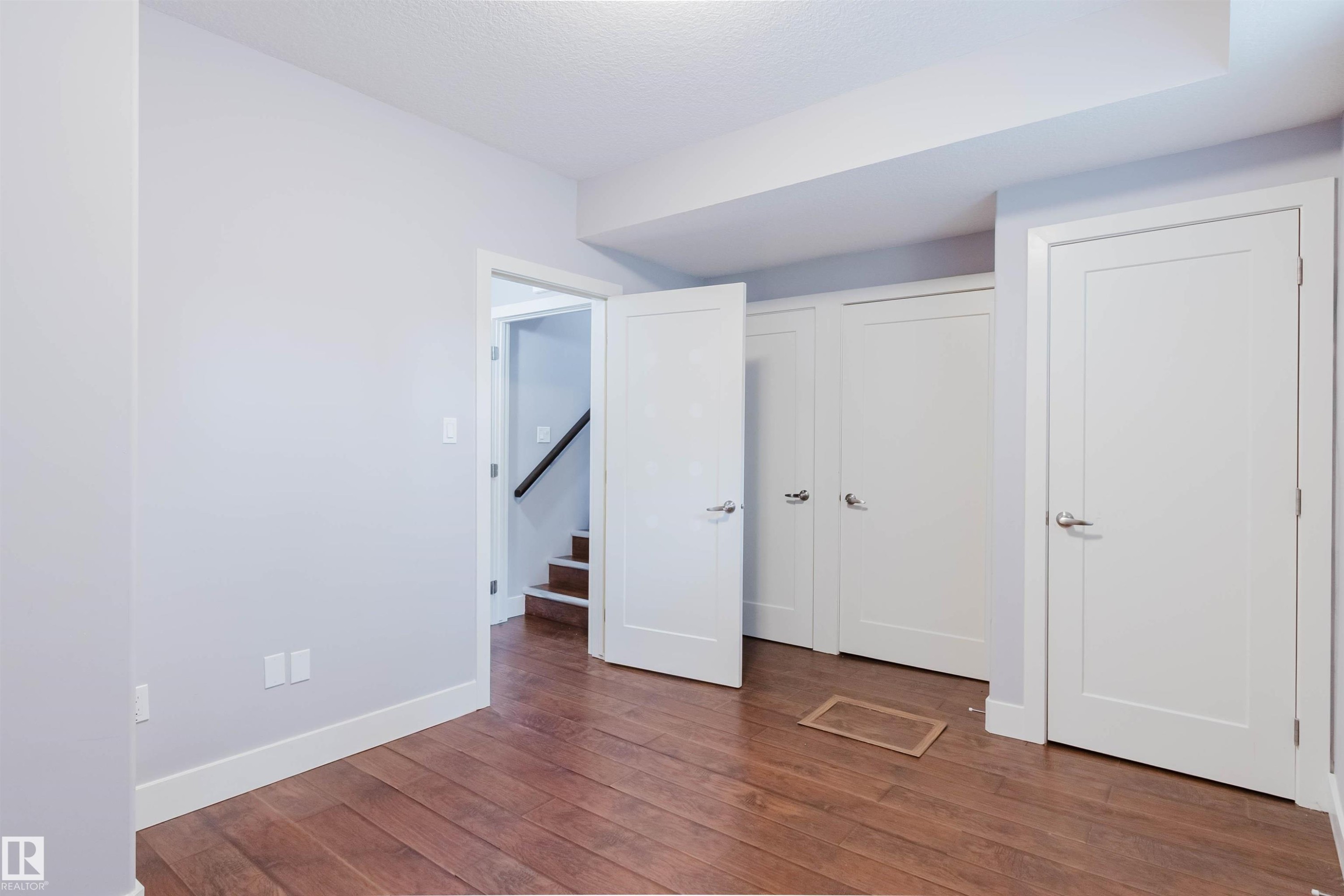 Interior space featuring wood-finish flooring, white trim, and multiple white doors with brushed nickel hardware - 10626 81 Avenue Nw, Edmonton, AB - Indoor Photo Showing Other Room