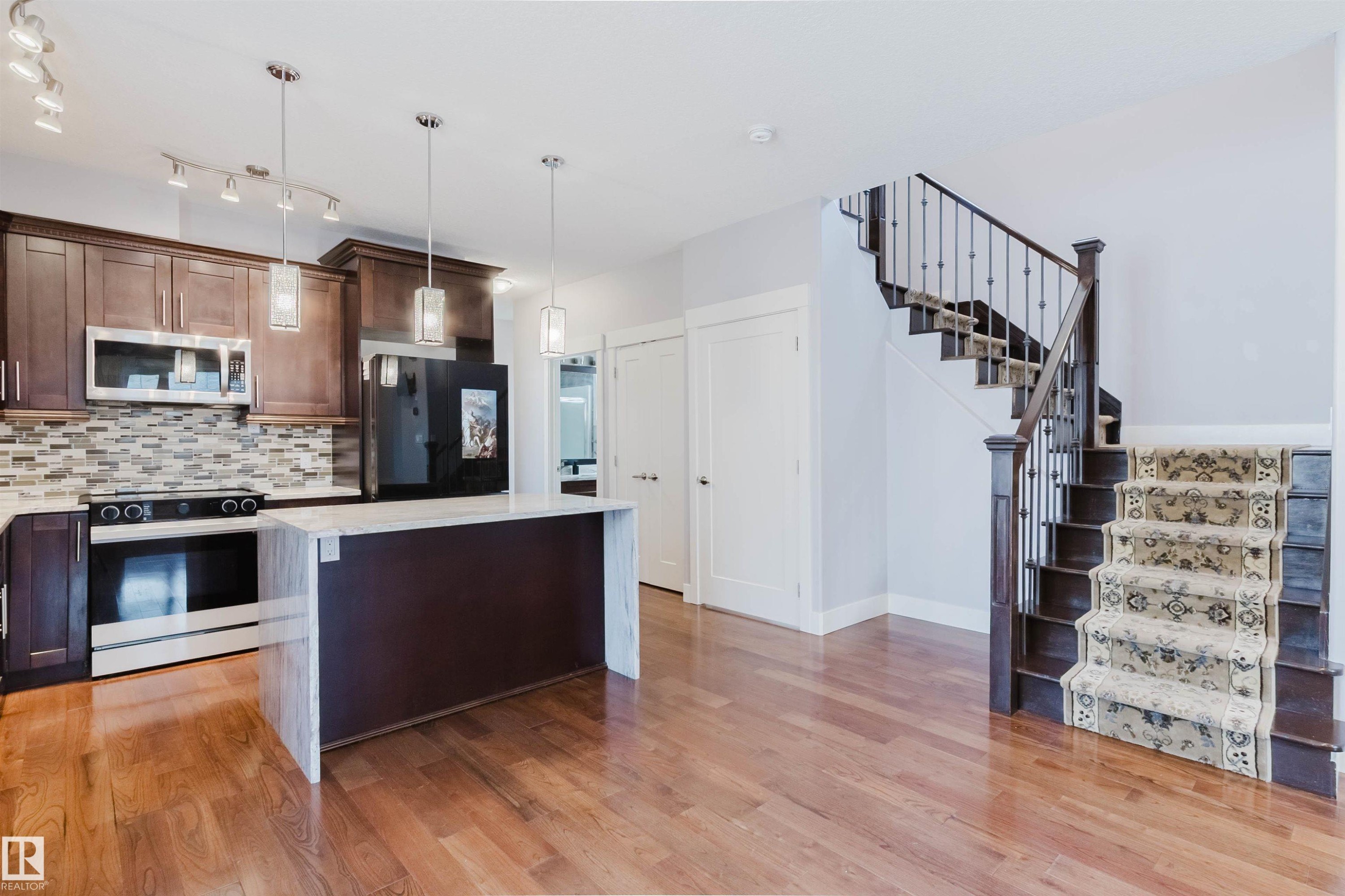 Open-concept living area featuring rich wood-finish flooring - 10626 81 Avenue Nw, Edmonton, AB - Indoor Photo Showing Kitchen With Upgraded Kitchen