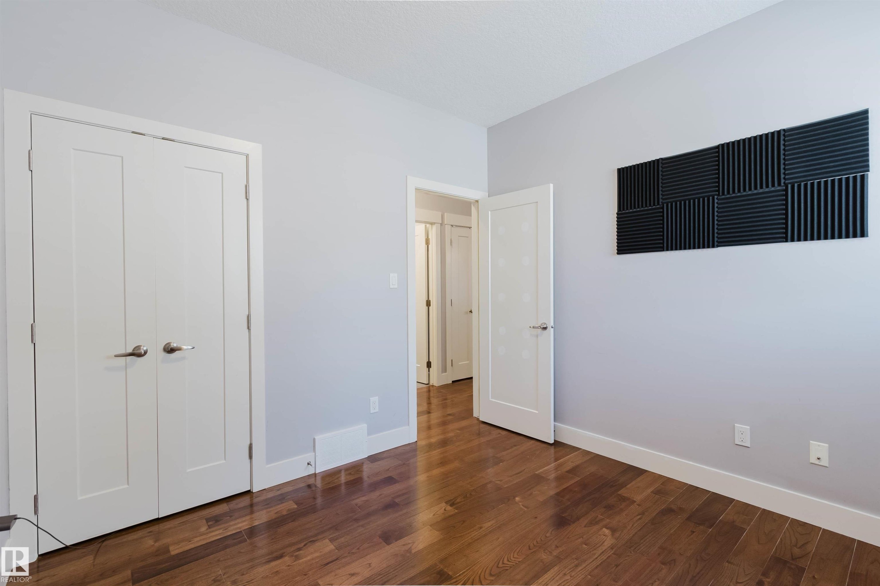 Hardwood-style flooring throughout this room, featuring light gray walls, white trim, and white interior doors - 10626 81 Avenue Nw, Edmonton, AB - Indoor Photo Showing Other Room