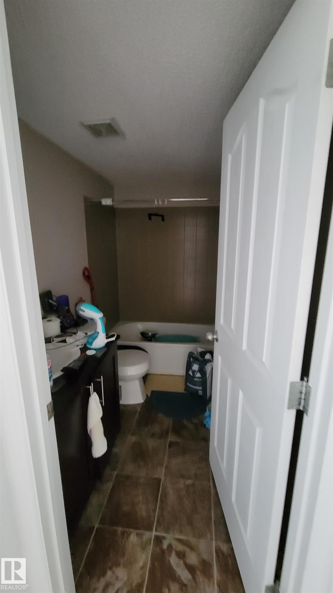 Bathroom featuring dark wood-finish vanity with countertop, white toilet, and tile flooring - #415 12045 22 Av Sw, Edmonton, AB - Indoor Photo Showing Bathroom