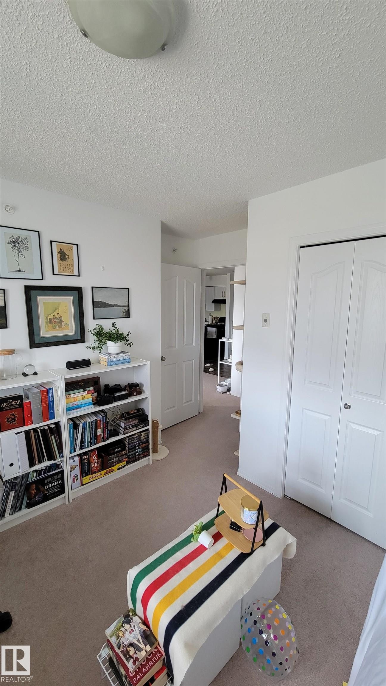 Recessed lighting fixture illuminating a room with white walls, textured ceiling, and carpet flooring - #415 12045 22 Av Sw, Edmonton, AB - Indoor Photo Showing Other Room