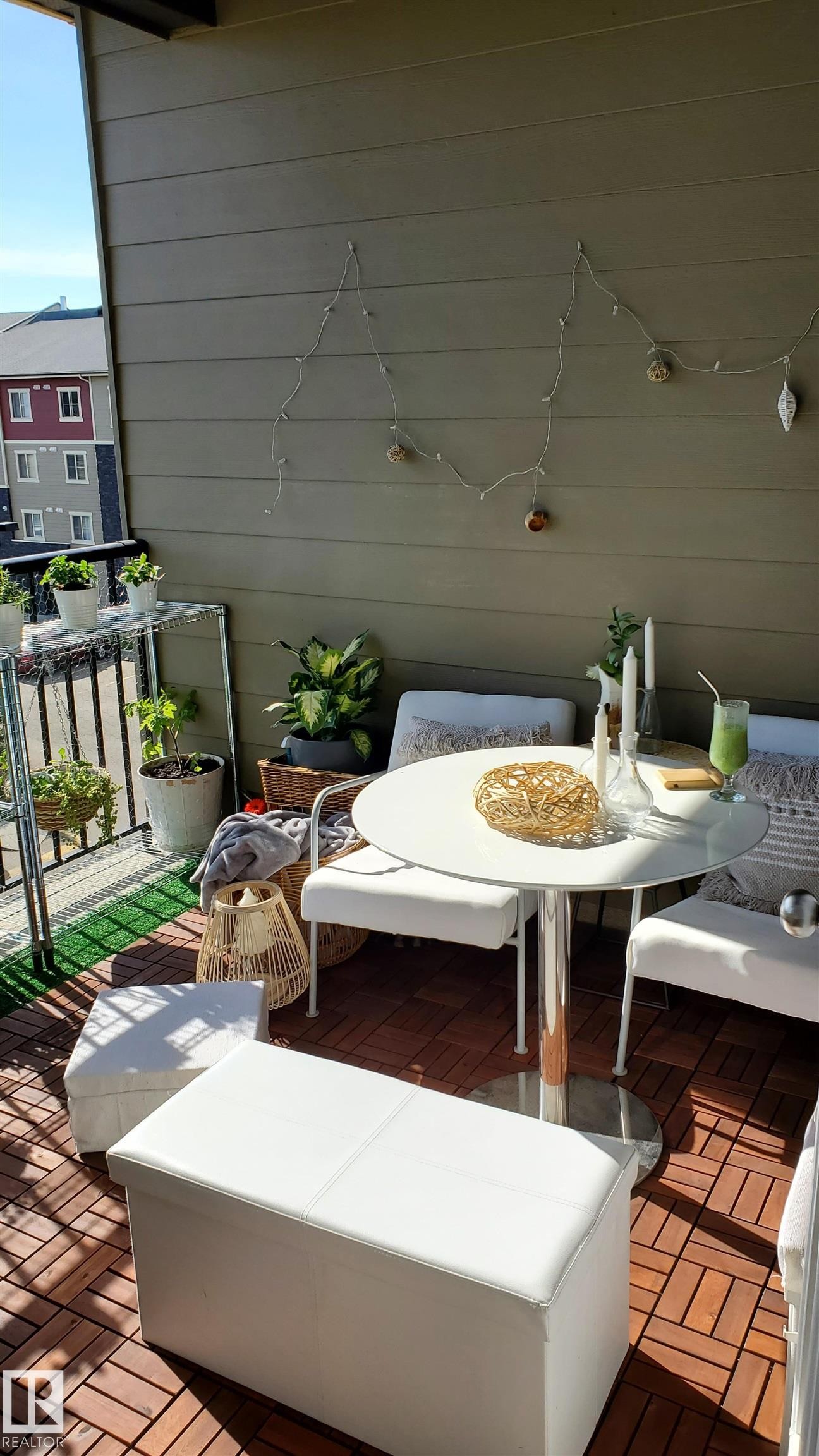 Balcony featuring wood-finish floor tiles, a painted horizontal siding wall, and a black metal railing - #415 12045 22 Av Sw, Edmonton, AB - With Exterior