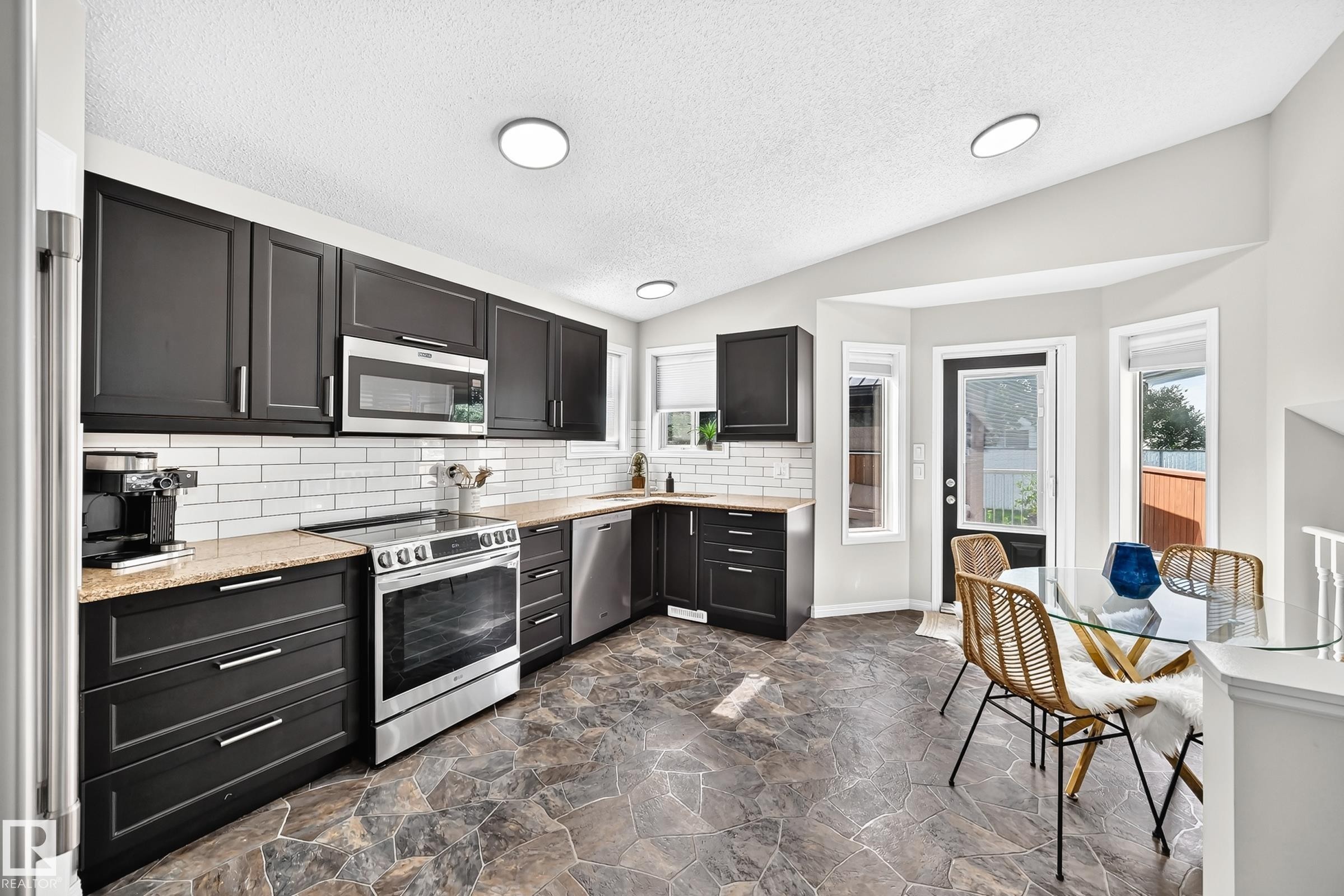 Modern kitchen featuring black cabinetry, light-toned countertops, and a white subway tile backsplash - 3729 131A Avenue Nw, Edmonton, AB - Indoor Photo Showing Kitchen With Upgraded Kitchen