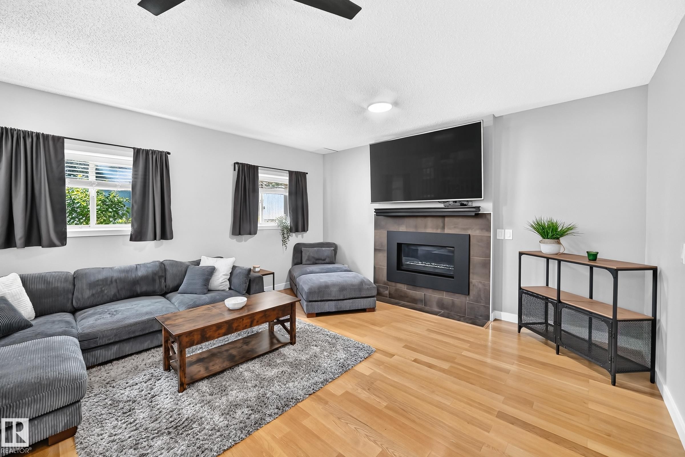 Living area featuring light wood-finish flooring, light gray walls, and multiple windows - 3729 131A Avenue Nw, Edmonton, AB - Indoor Photo Showing Living Room With Fireplace