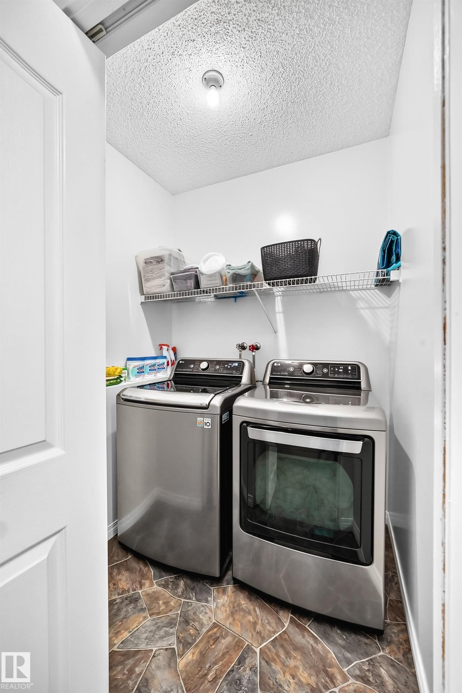 Dedicated laundry area with stone-look flooring, white walls, and a convenient wire shelf system - 3729 131A Avenue Nw, Edmonton, AB - Indoor Photo Showing Laundry Room