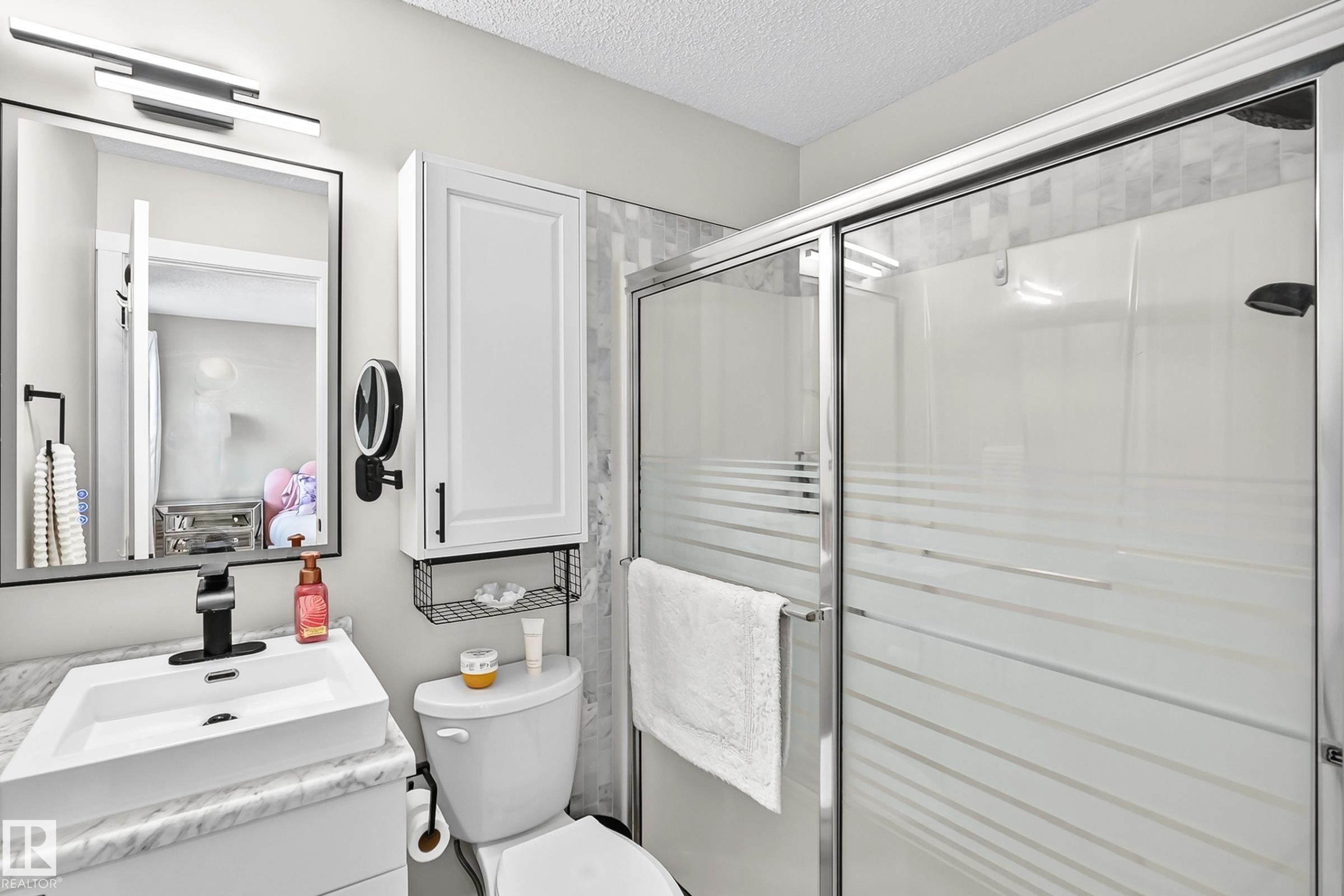 Three-piece bathroom featuring a shower with sliding glass doors and striped privacy film, a vanity with a rectangular vessel sink, and a wall-mounted medicine cabinet with integrated shelving - 3729 131A Avenue Nw, Edmonton, AB - Indoor Photo Showing Bathroom