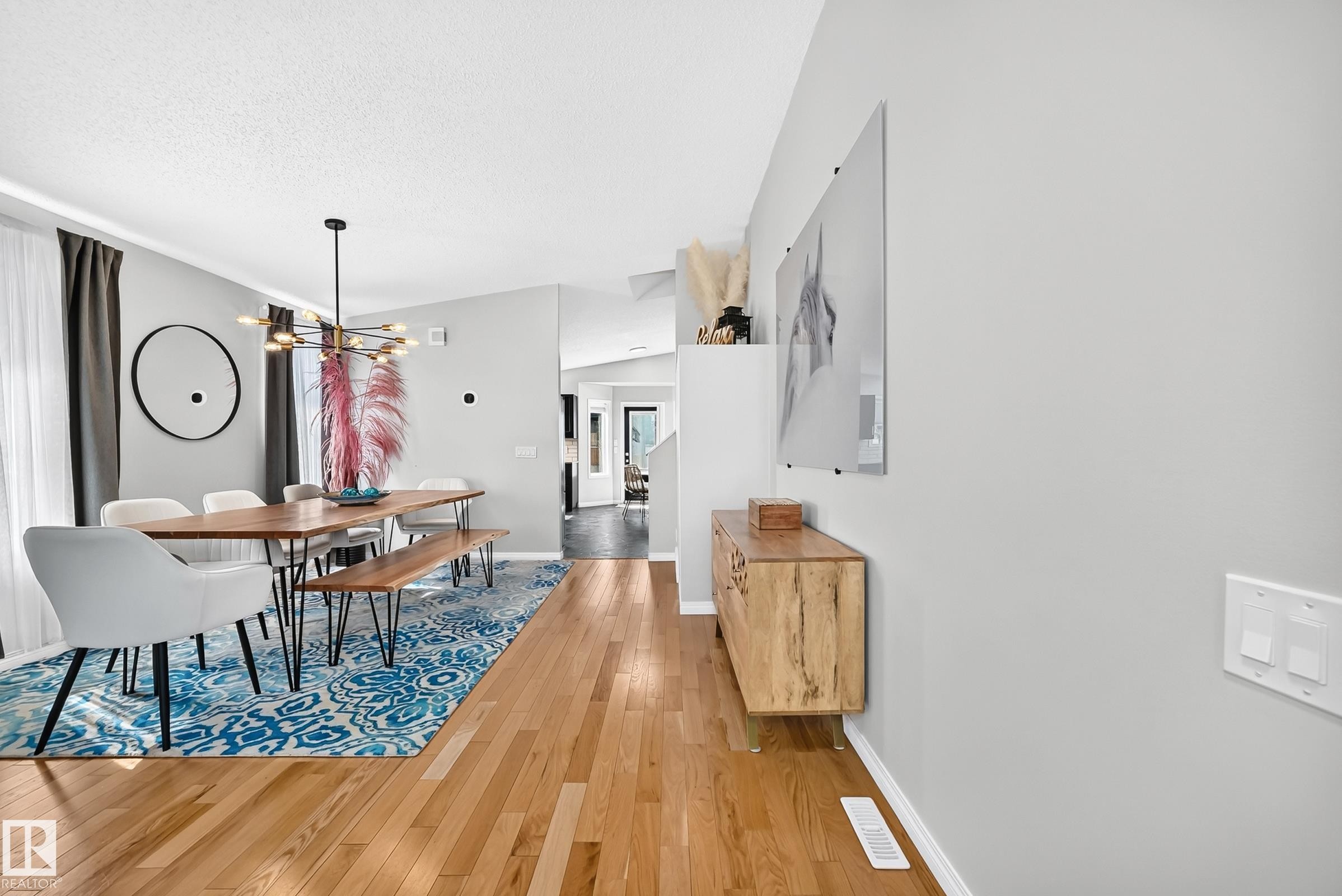 Dining area featuring wood-finish flooring, a contemporary chandelier, light gray wall finishes, and a dedicated wall space for art - 3729 131A Avenue Nw, Edmonton, AB - Indoor
