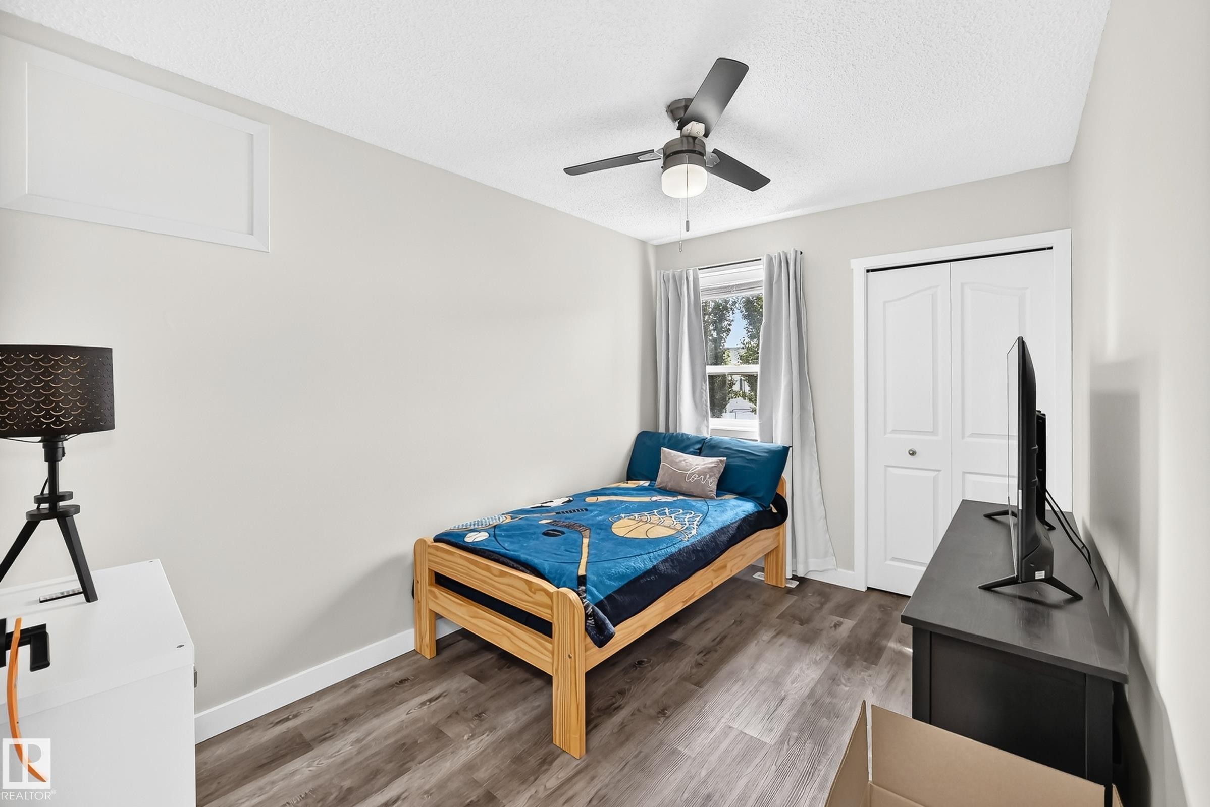 Room featuring wood-finish flooring, a double-door closet with bi-fold doors, and a ceiling fan with integrated lighting - 3729 131A Avenue Nw, Edmonton, AB - Indoor Photo Showing Bedroom
