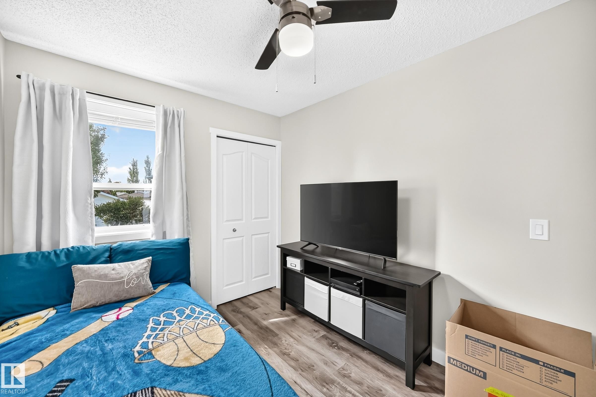 Interior room featuring wood-finish flooring, a white bi-fold closet door, and a ceiling fan with integrated lighting - 3729 131A Avenue Nw, Edmonton, AB - Indoor Photo Showing Bedroom