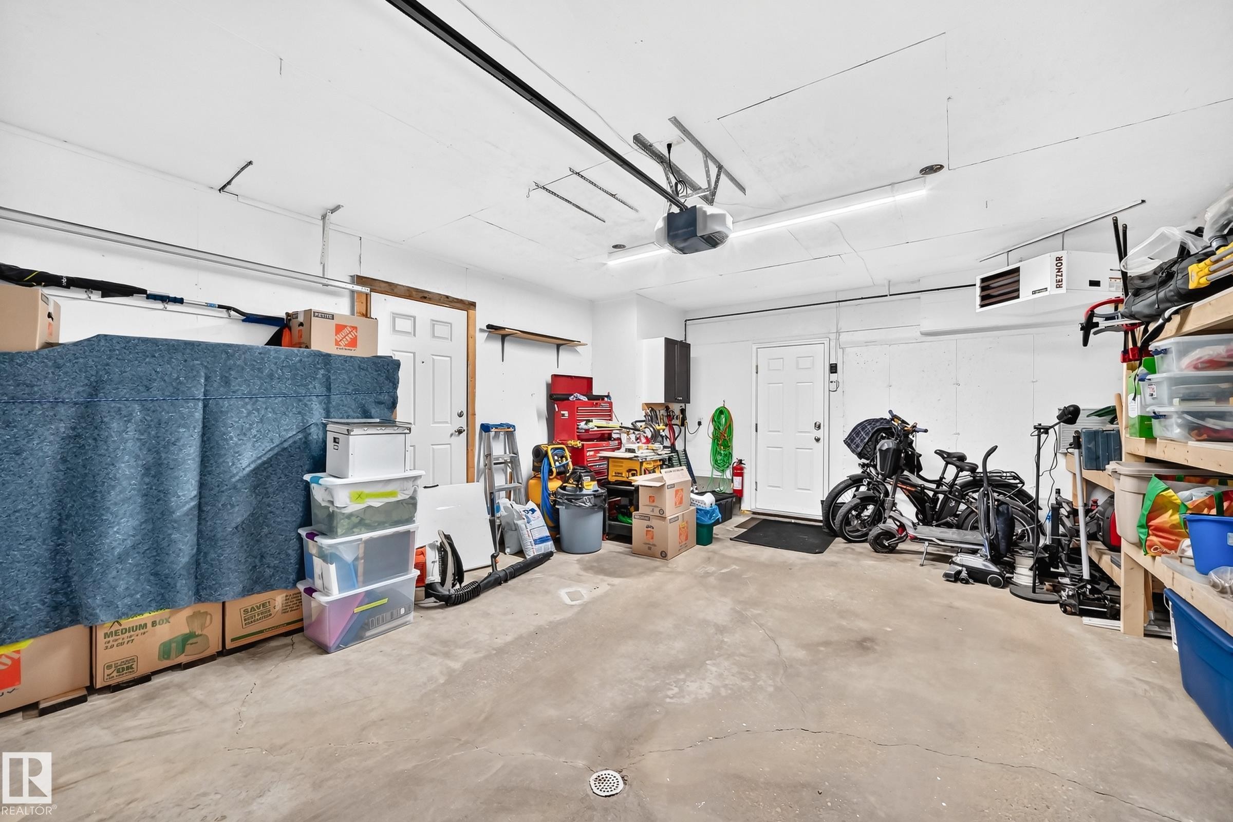 Spacious garage featuring a concrete floor, bright overhead lighting, and white walls - 3729 131A Avenue Nw, Edmonton, AB - Indoor Photo Showing Garage